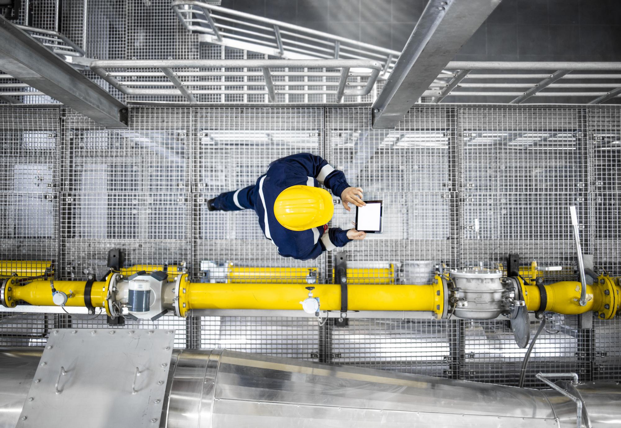 Top view of refinery worker walking by gas pipes