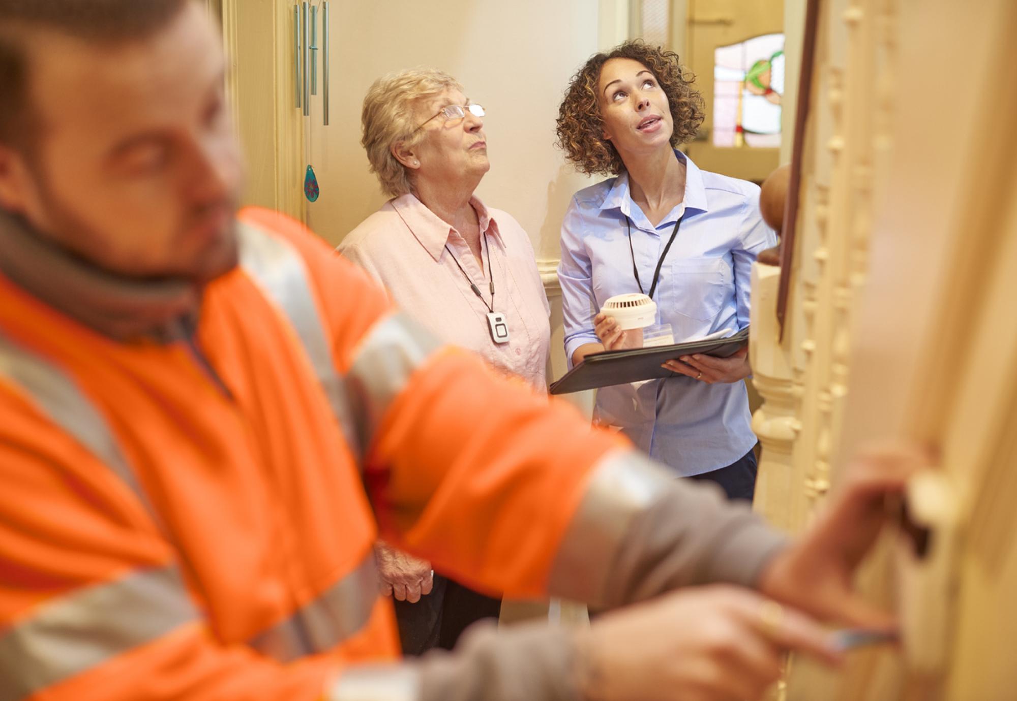 an alarm fitter fits an alarm in a senior woman's house