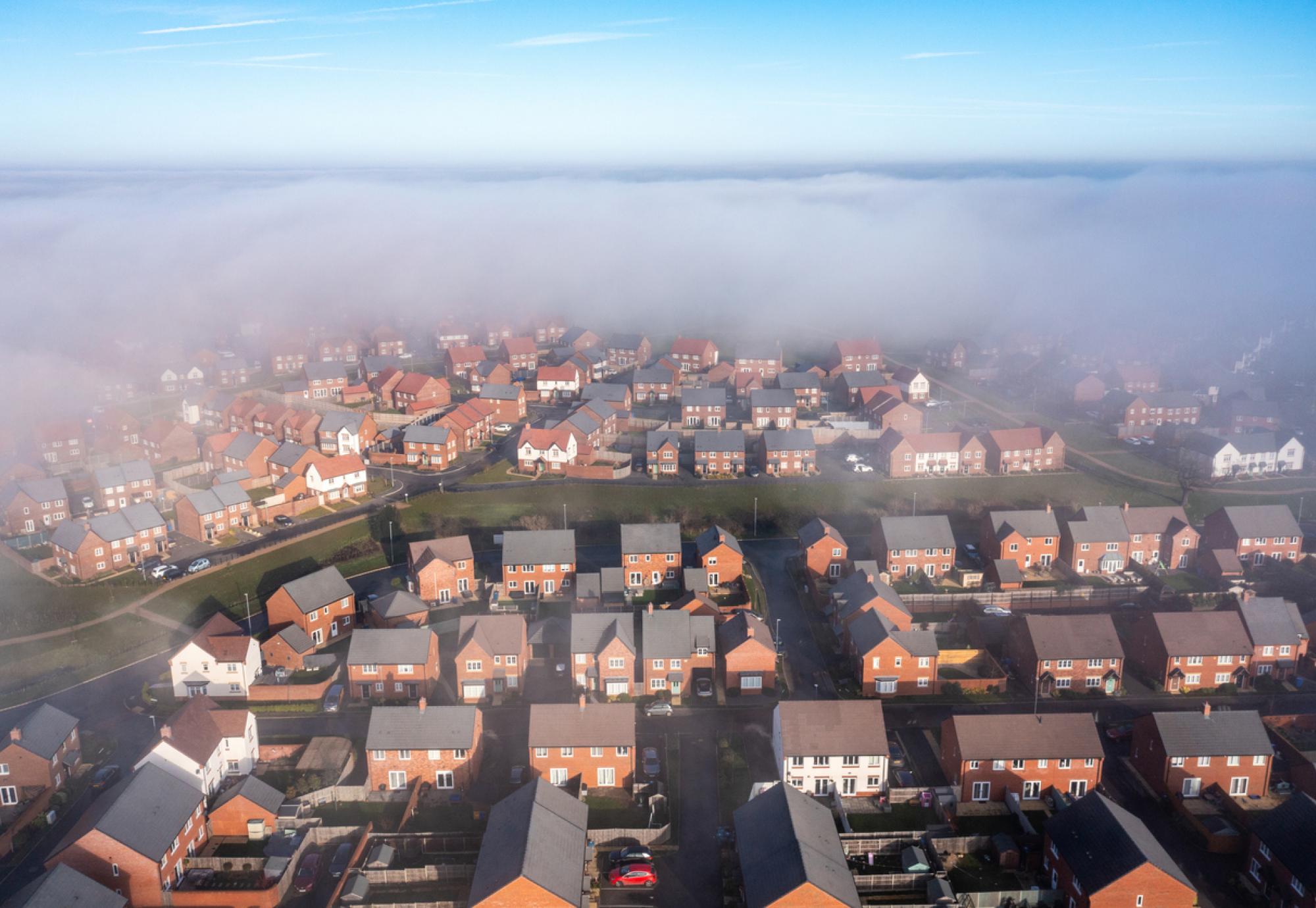 New estate with typical British houses and green gardens hidden by clouds