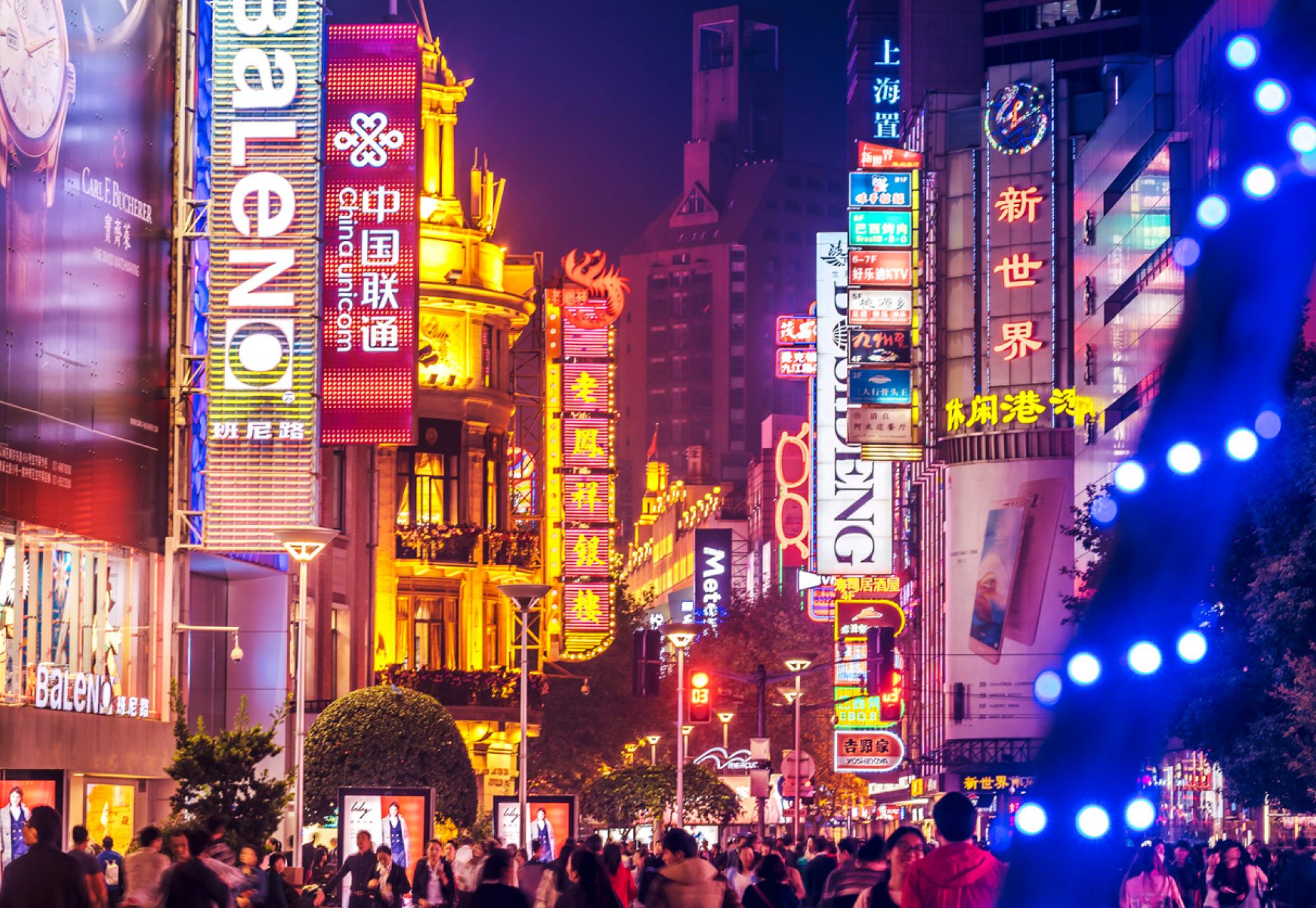 Crowds walk below neon signs on Nanjing Road, Shanghai