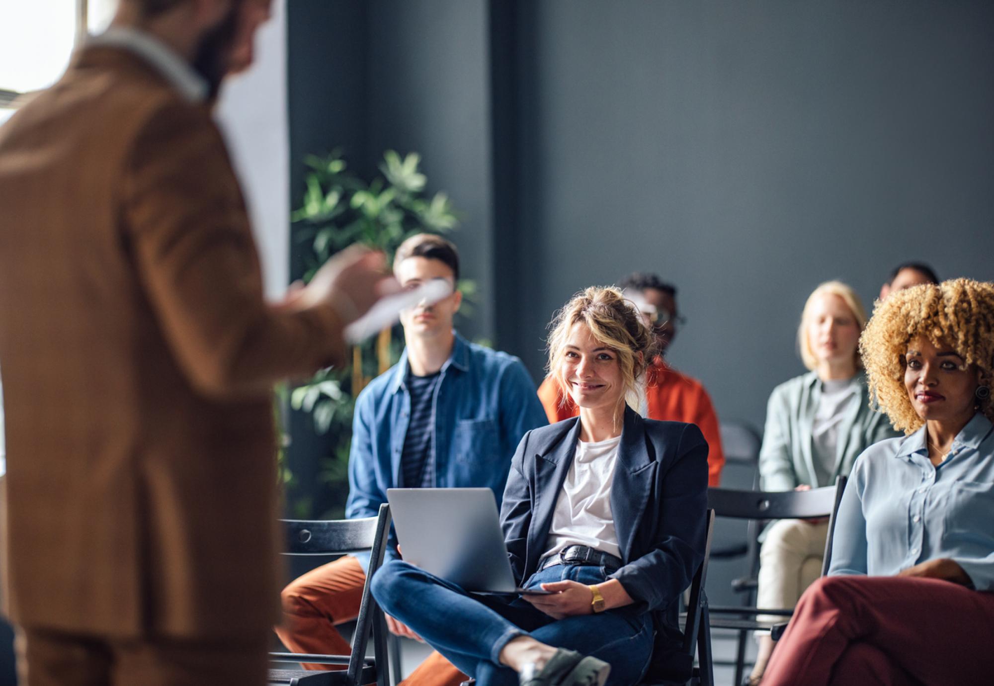 Group of men and women sitting and listening to a seminar.