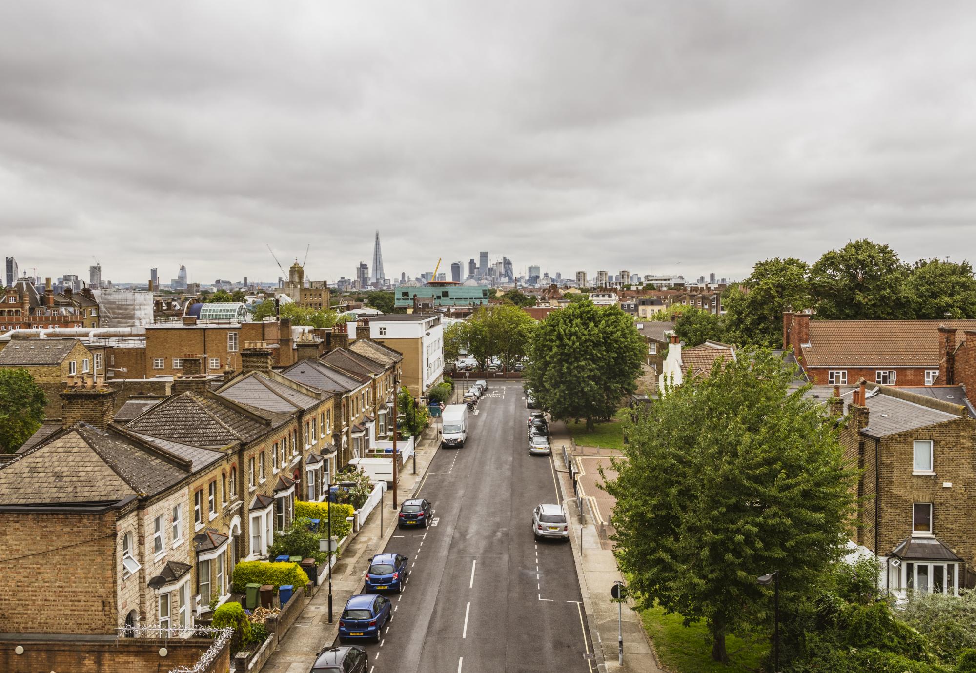 Peckham street with residential housing and the city skyline with skyscrapers on the horizon.