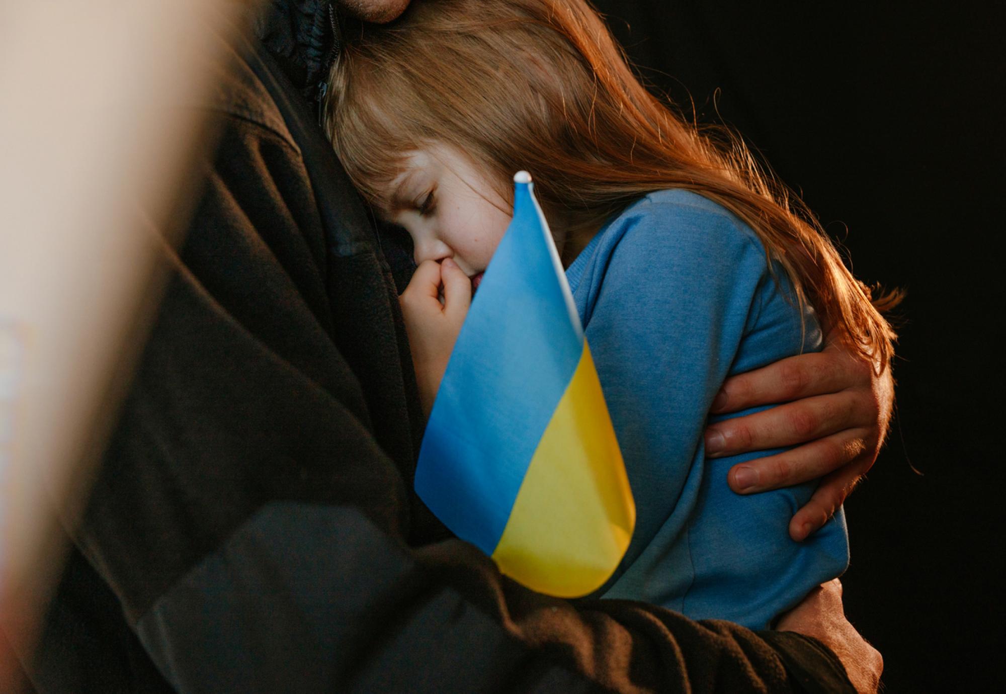 A Ukrainian refugee child with a Ukraine flag
