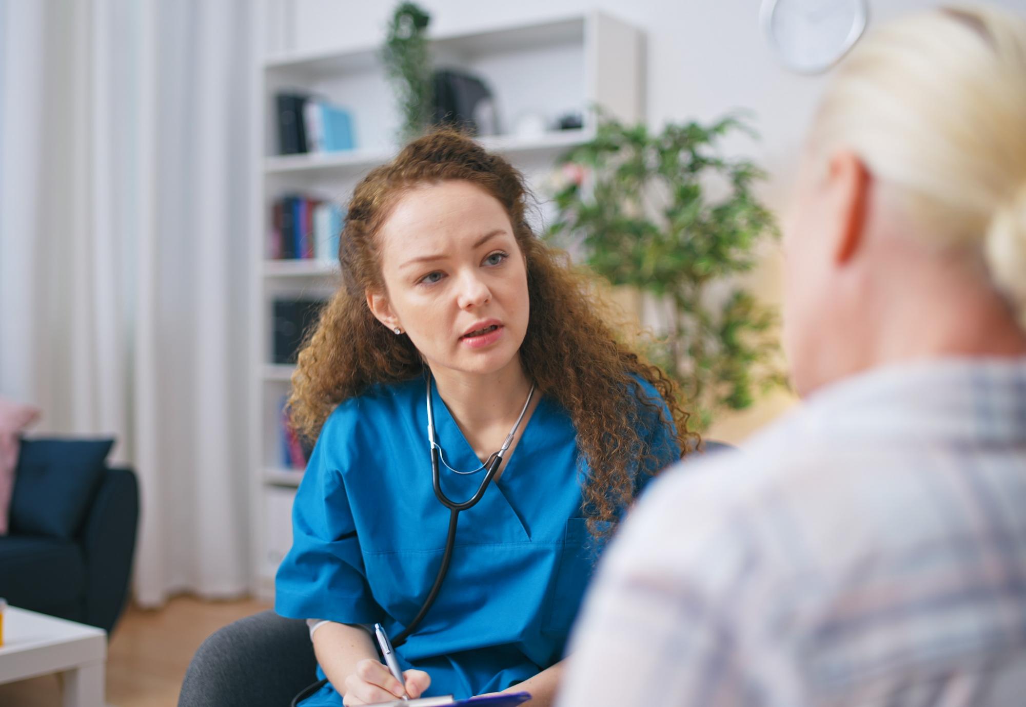 A therapist listens to the patient's complaints, fills out a medical form, and provides home care