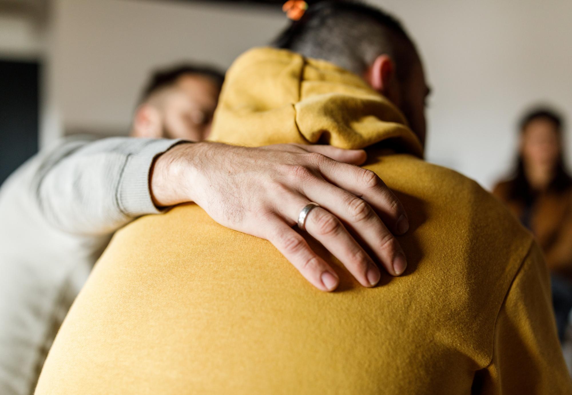 Close up shot of compassionate man embracing his friend