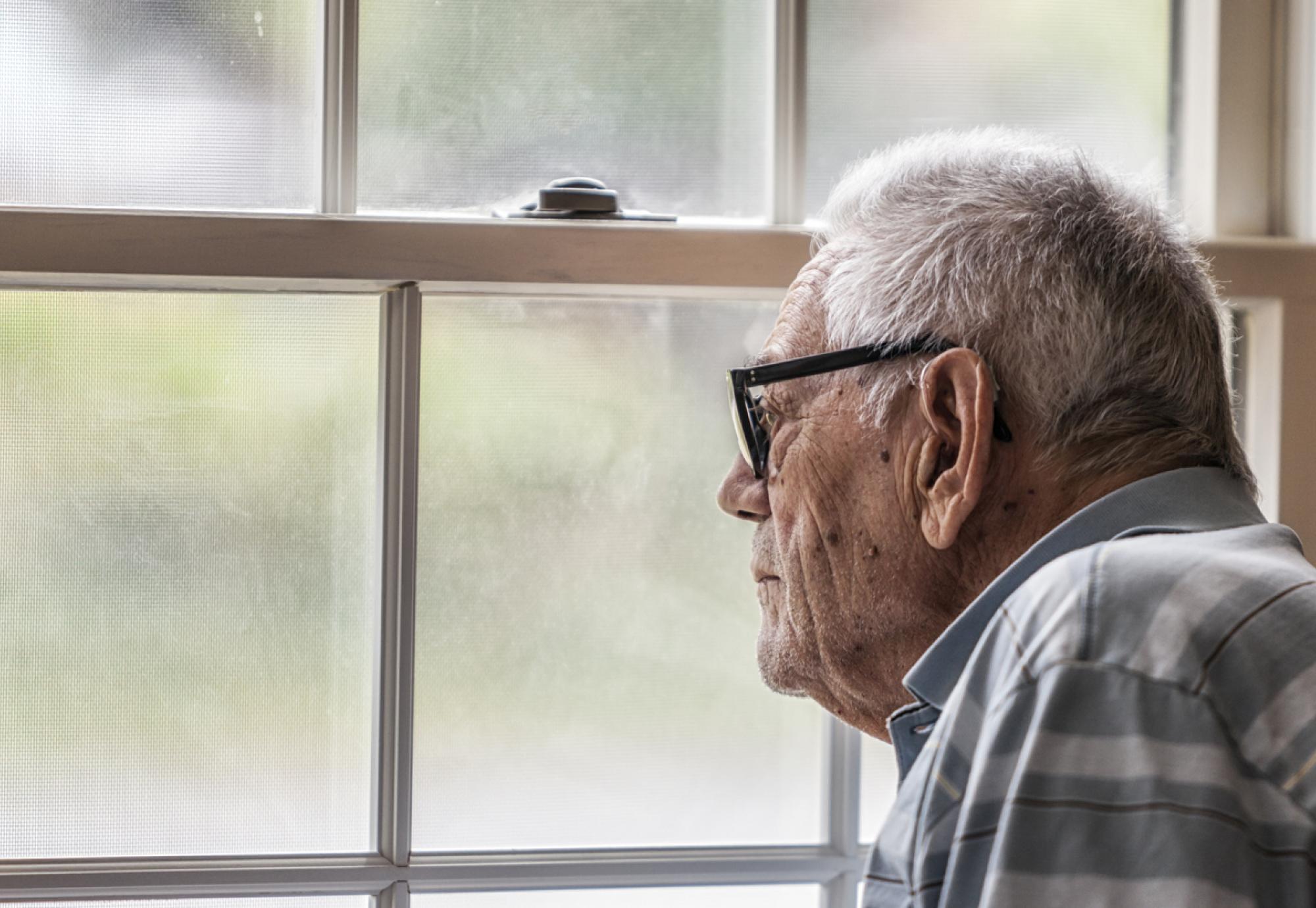 Wistful Senior Man Staring Through Hazy Window