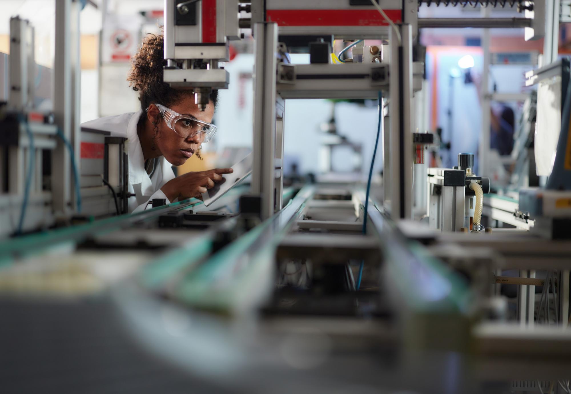 Young scientist using touchpad while working on machinery in a lab