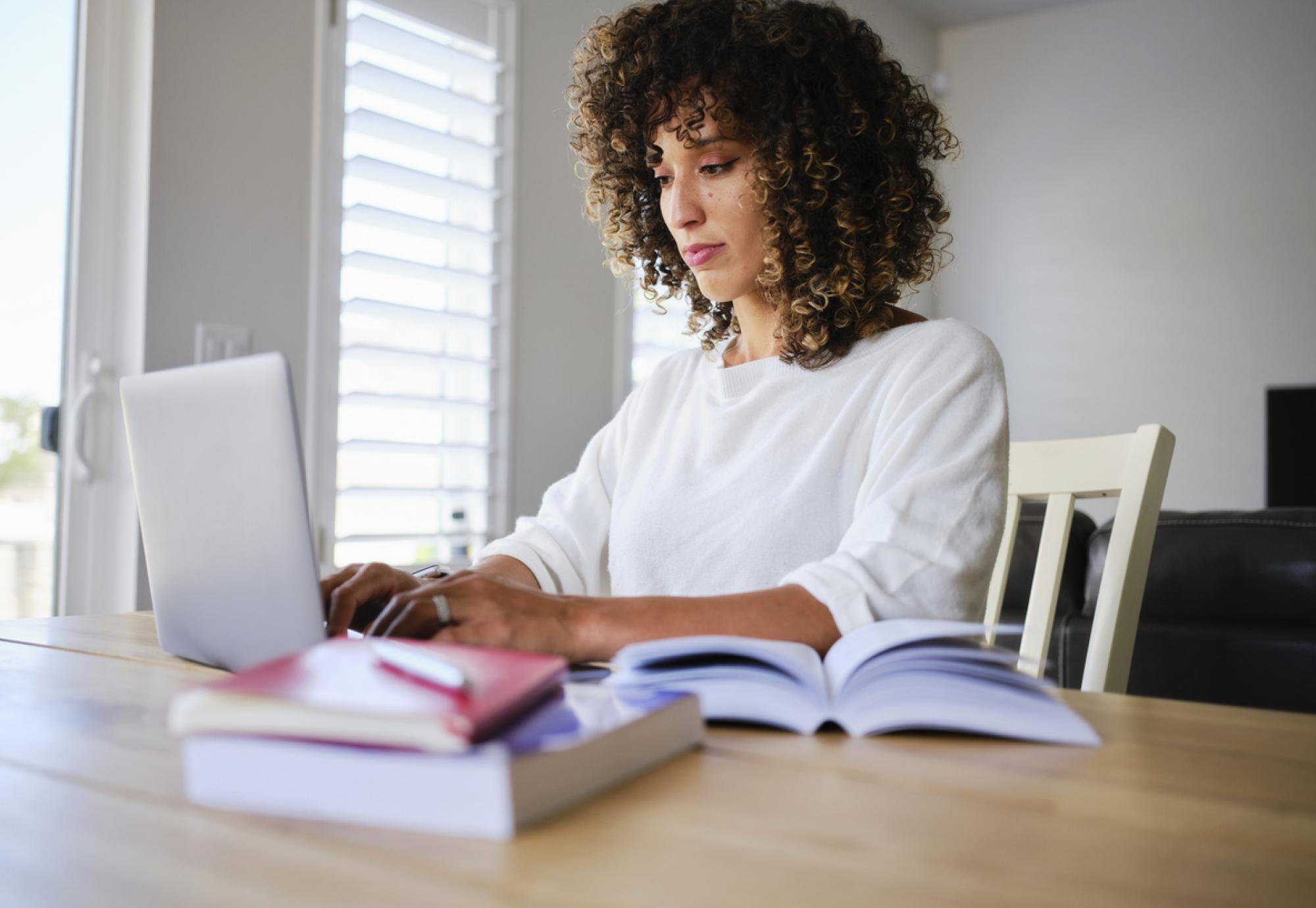 A young woman studying with a laptop computer in a home.