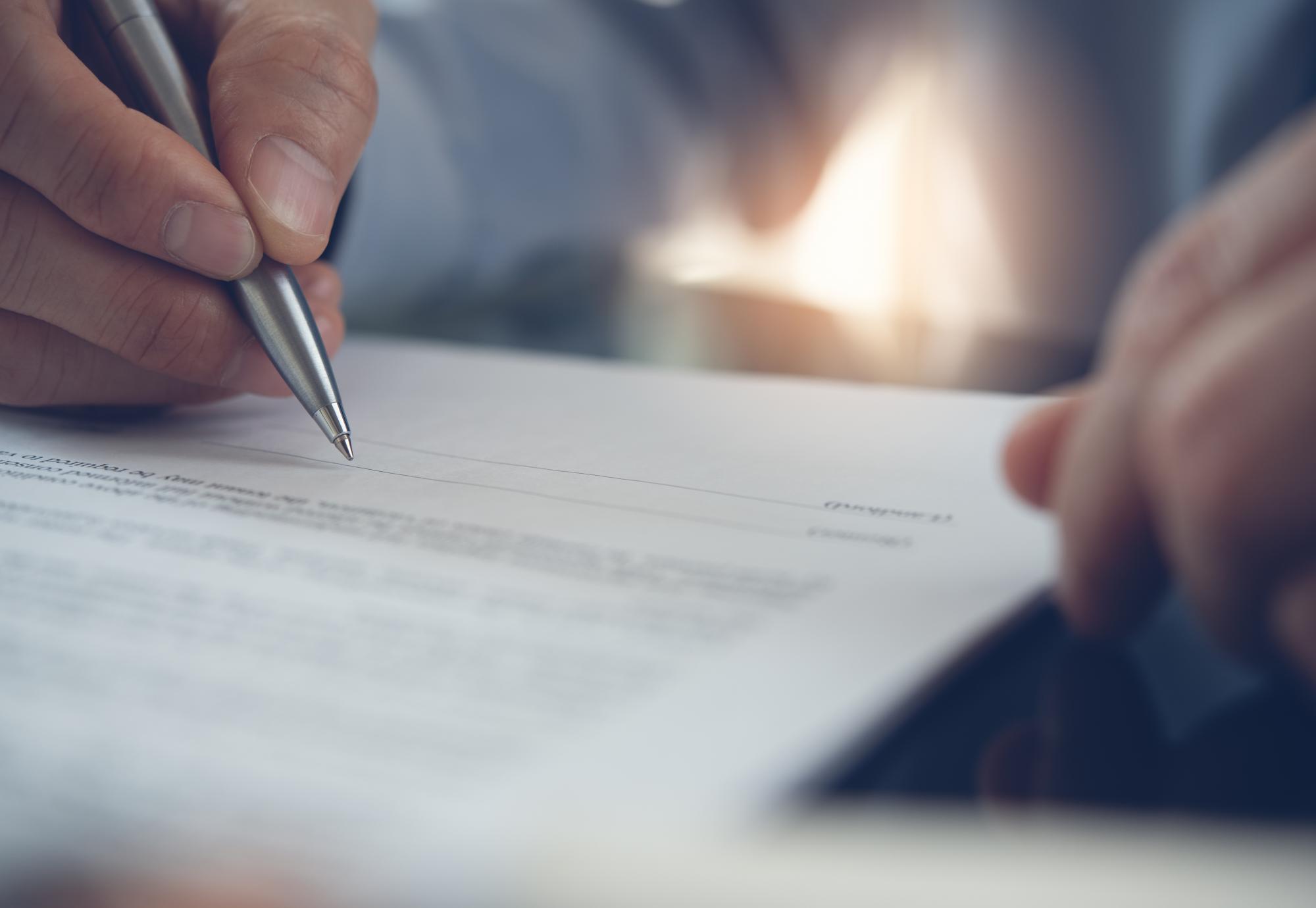 Businessman with pen in hand reading official business contract