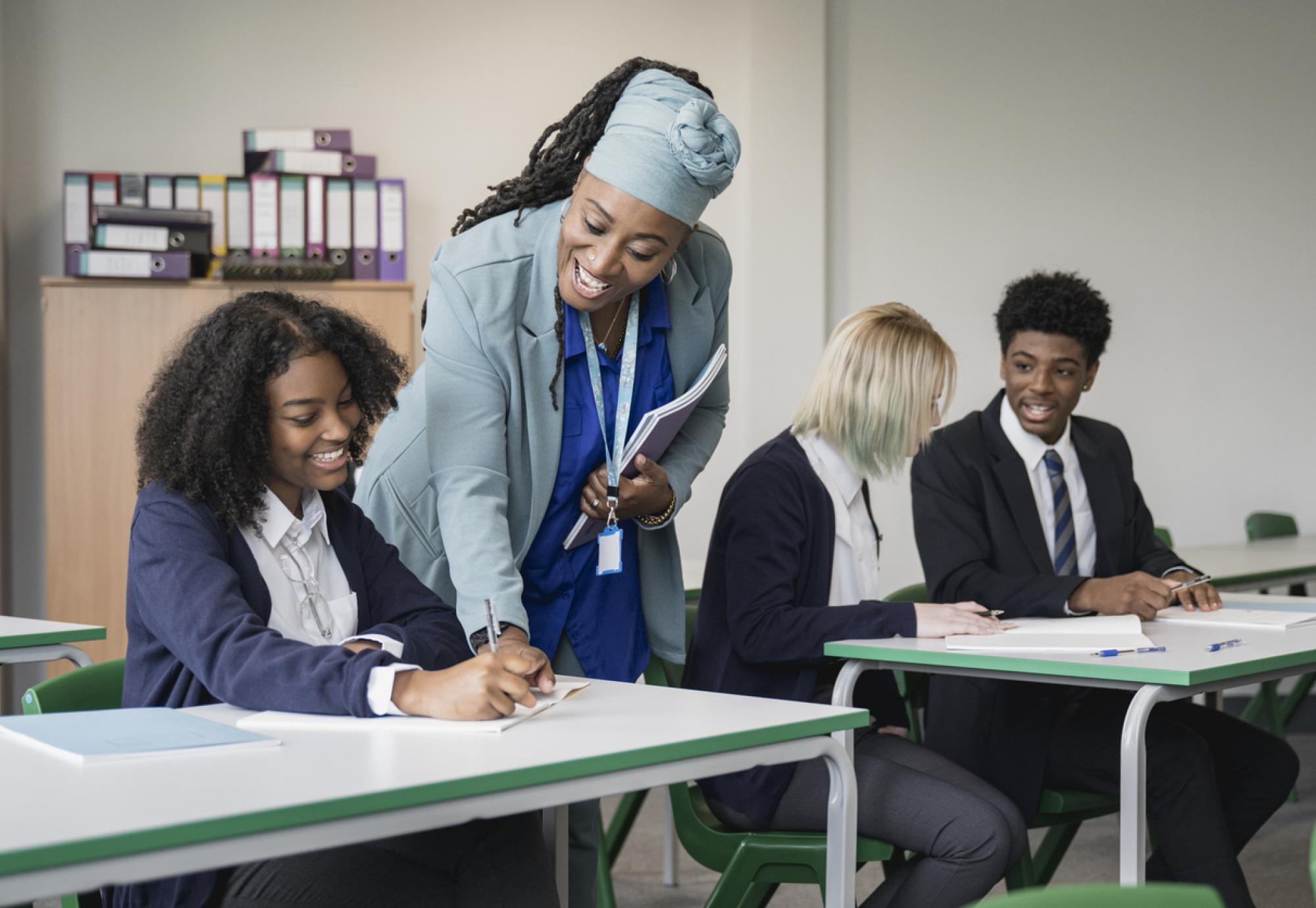 Multiracial group of teenagers in uniforms sitting together at desks