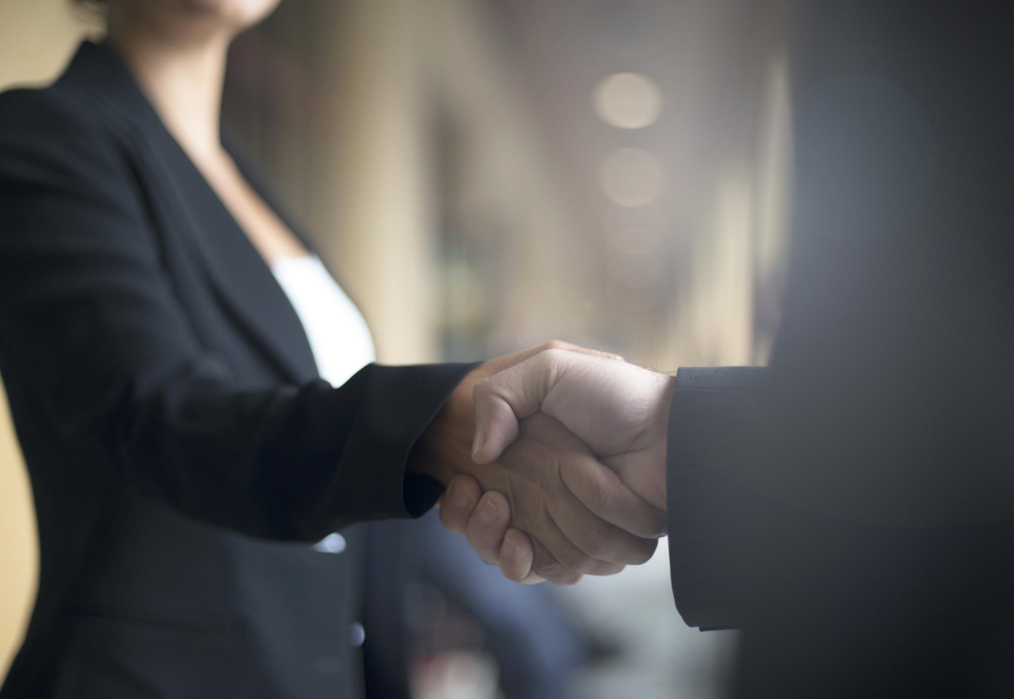 Two people shaking hands on business event.