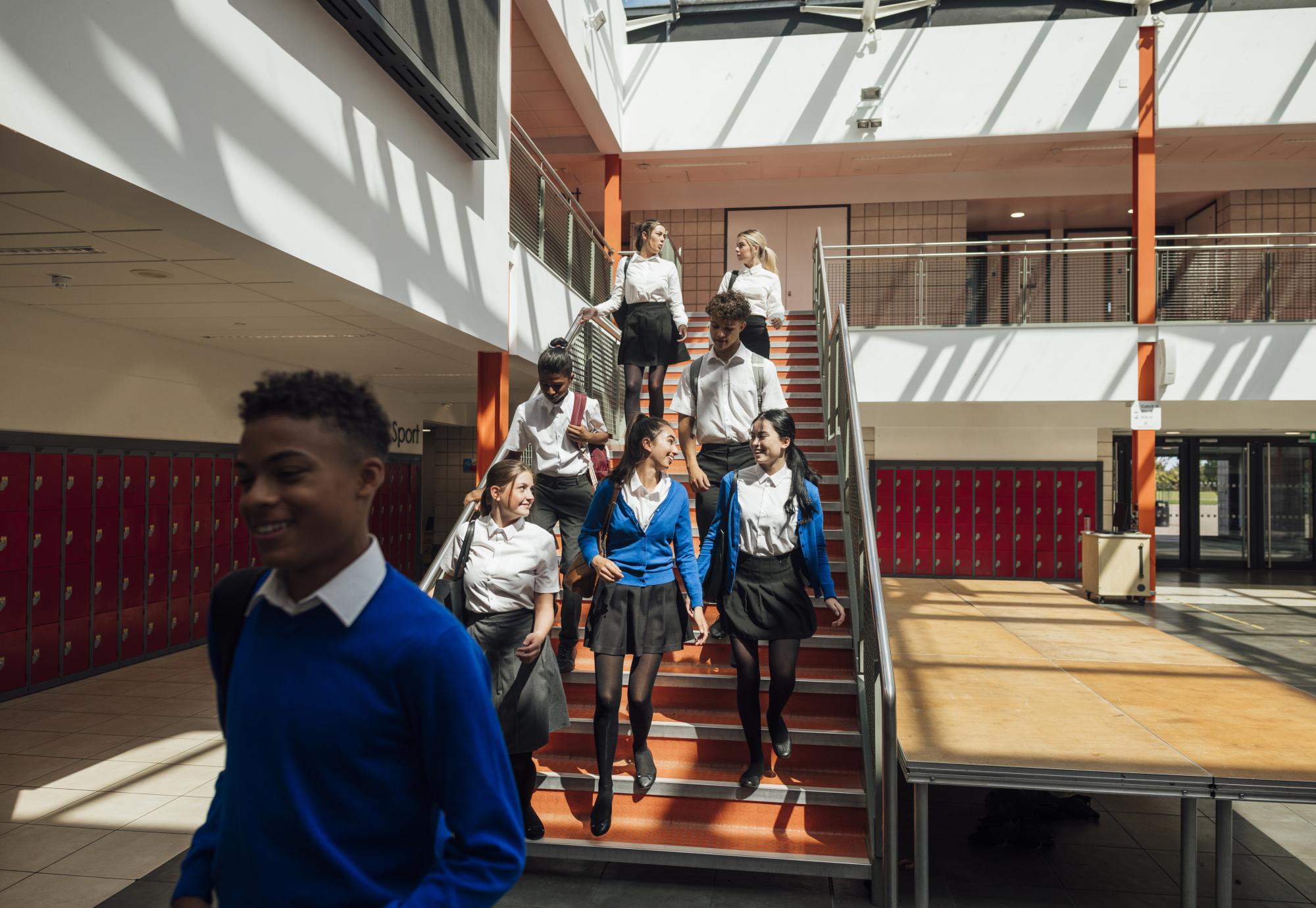 A wide angle view of a group of high school students who are rushing to their next class