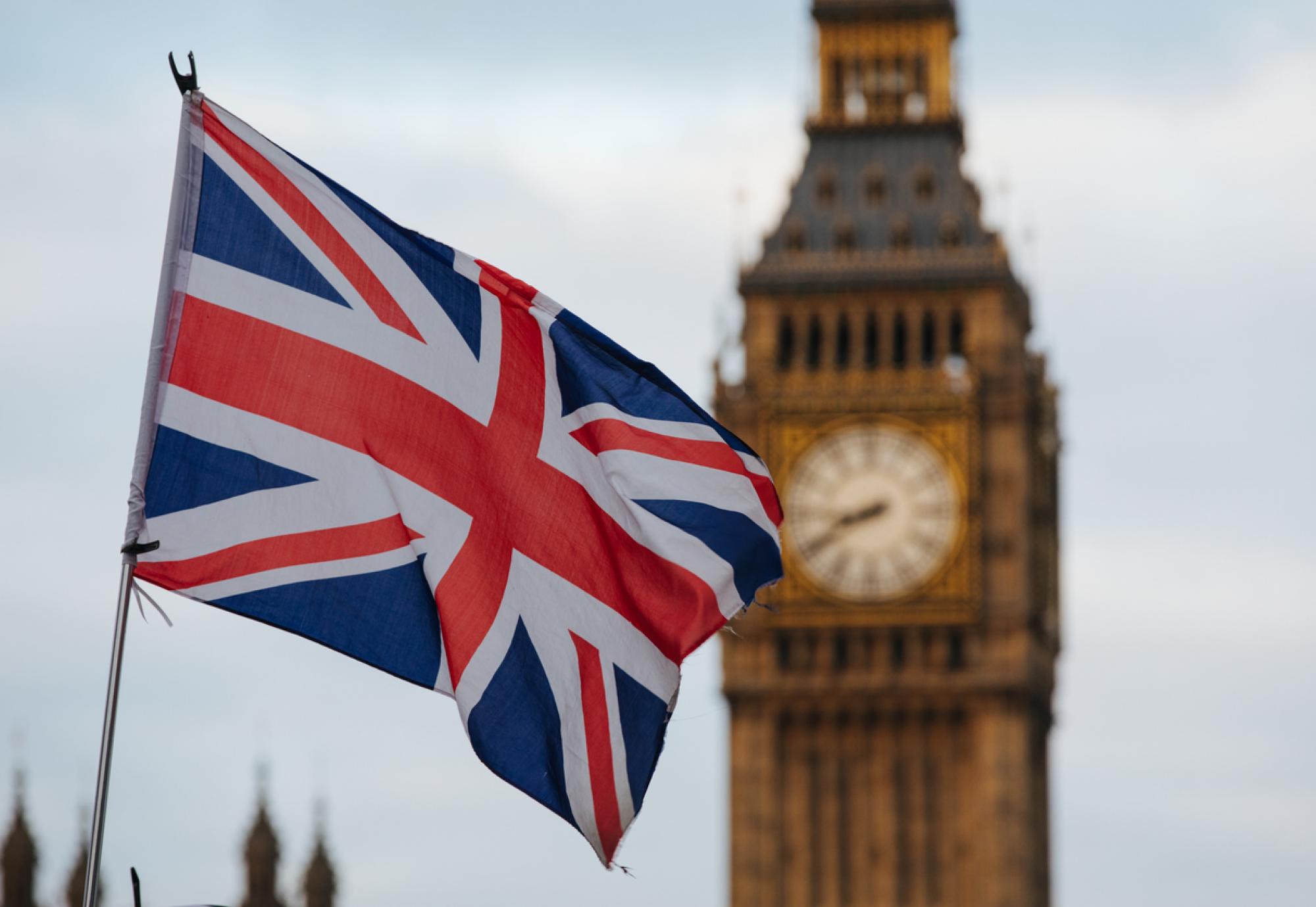 Big Ben with a UK flag in the foreground