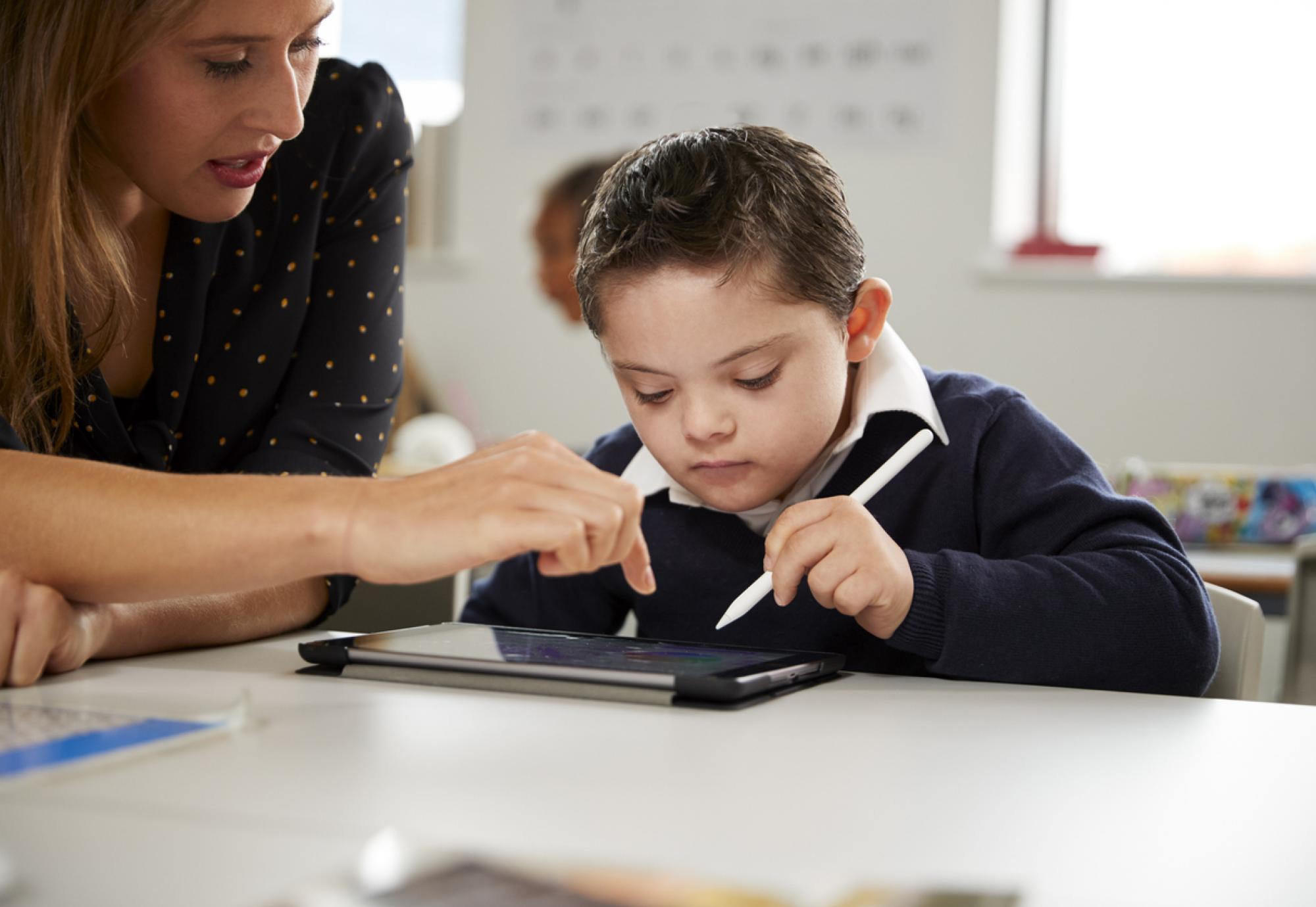 Young female teacher working with a Down syndrome schoolboy