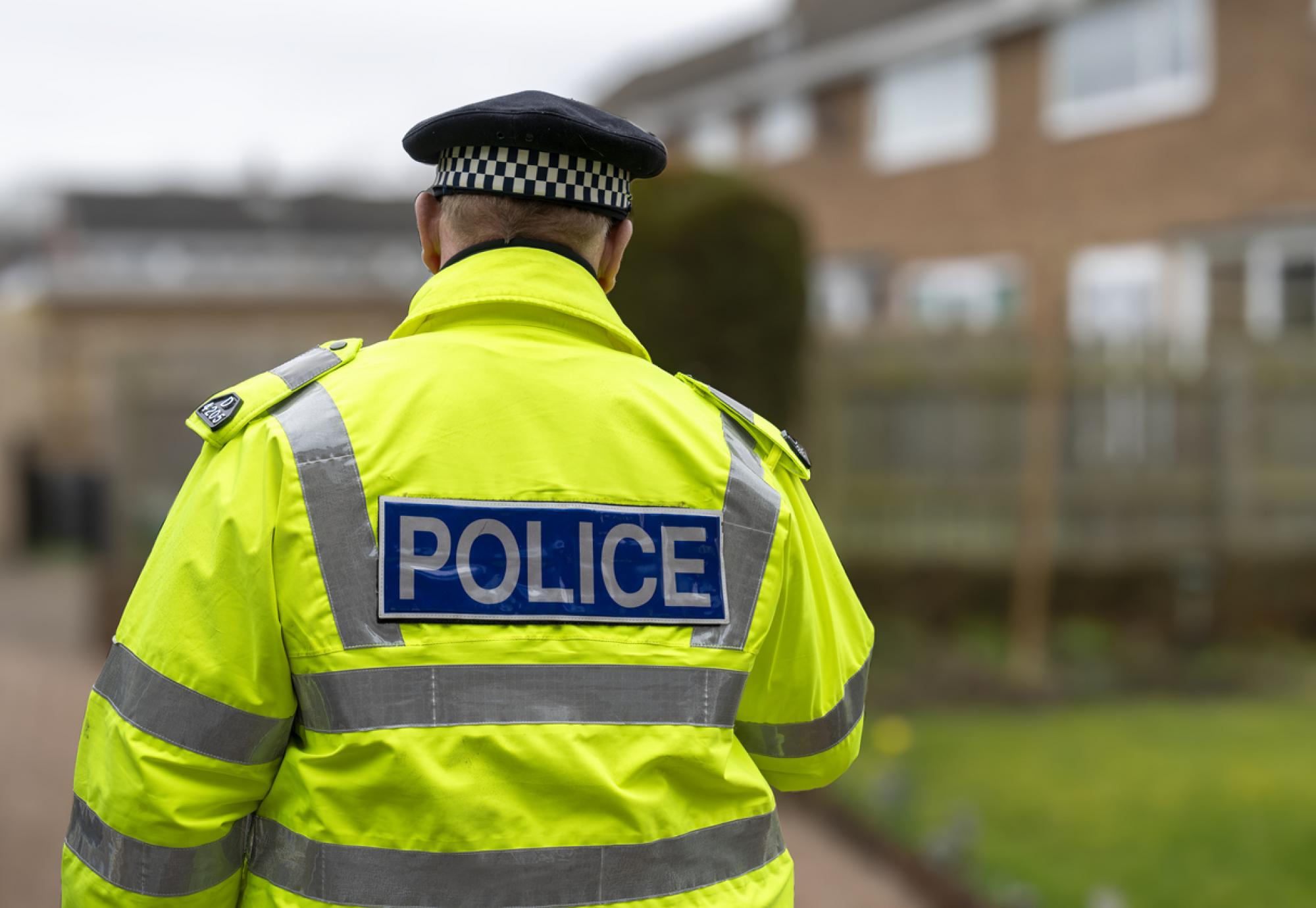 A policeman walking away from an elderly person's home.
