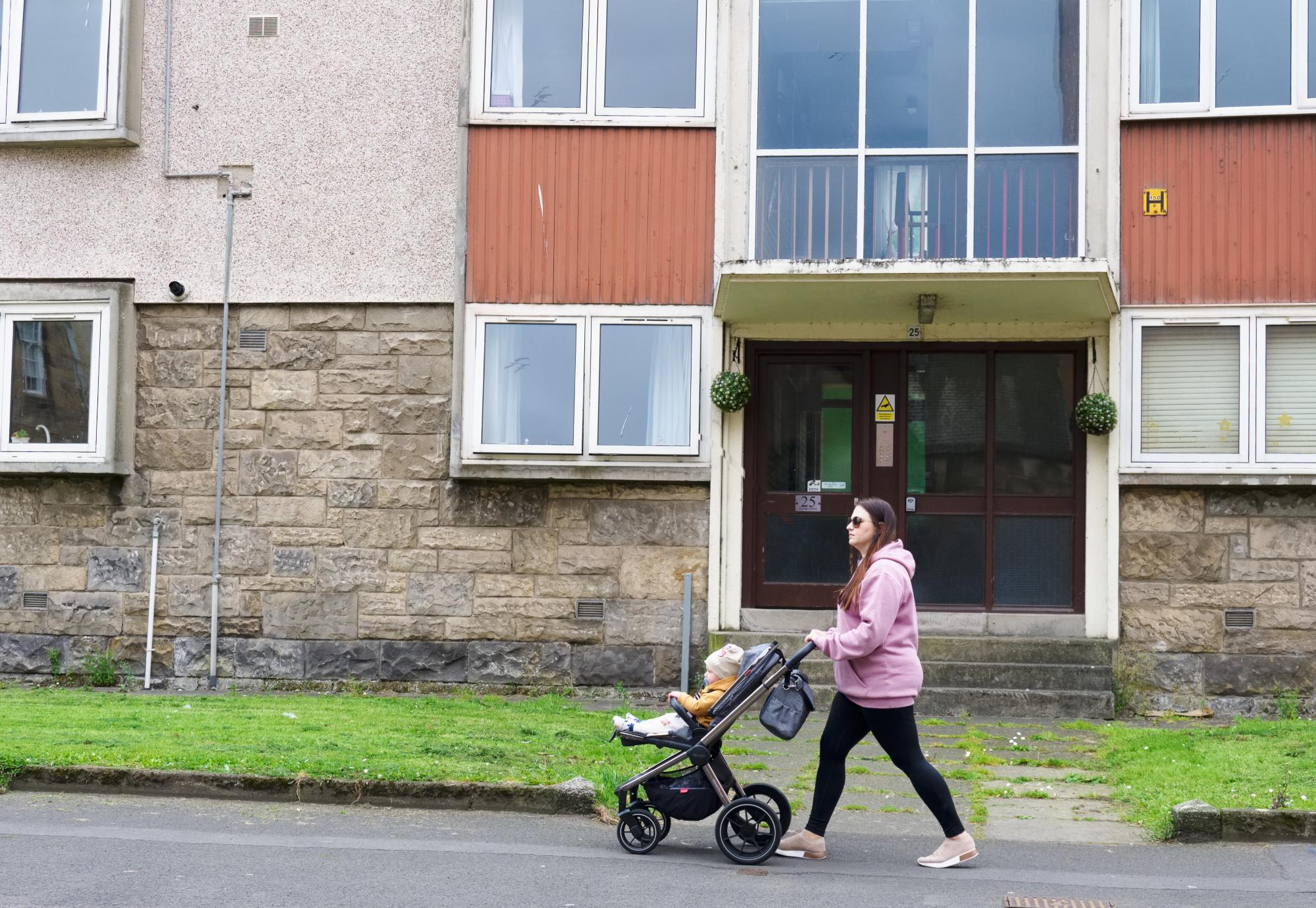 Mother and baby walking through a council estate