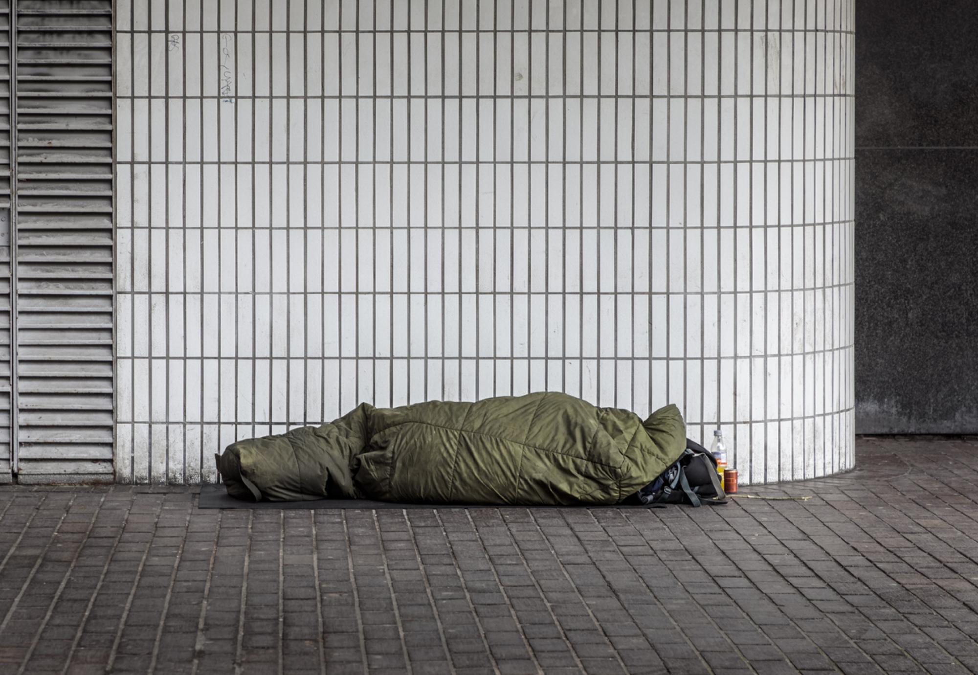 A homeless man in a sleeping bag outside Euston Station, London