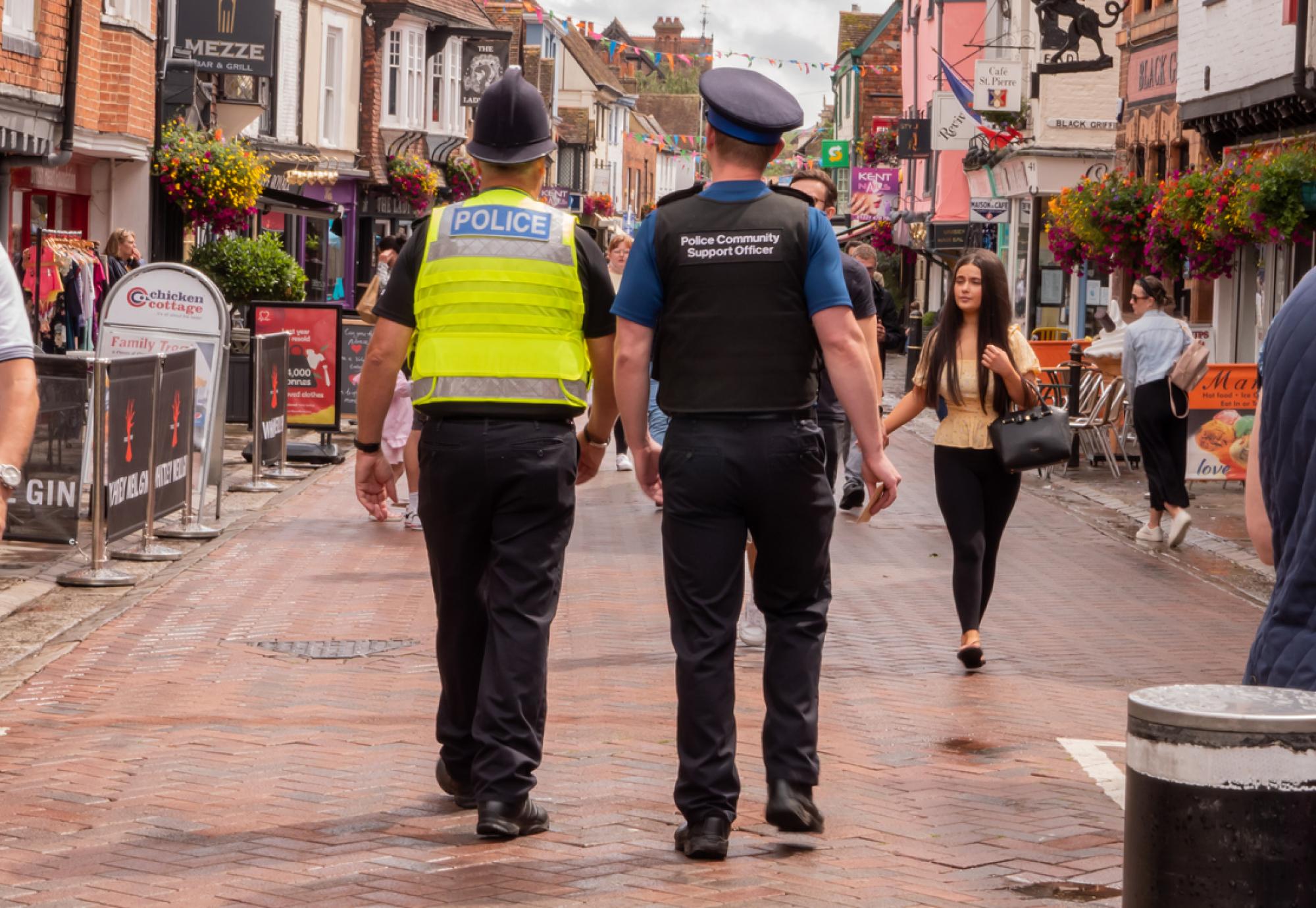 Policeman and Police Community Support Officer walking down a busy street