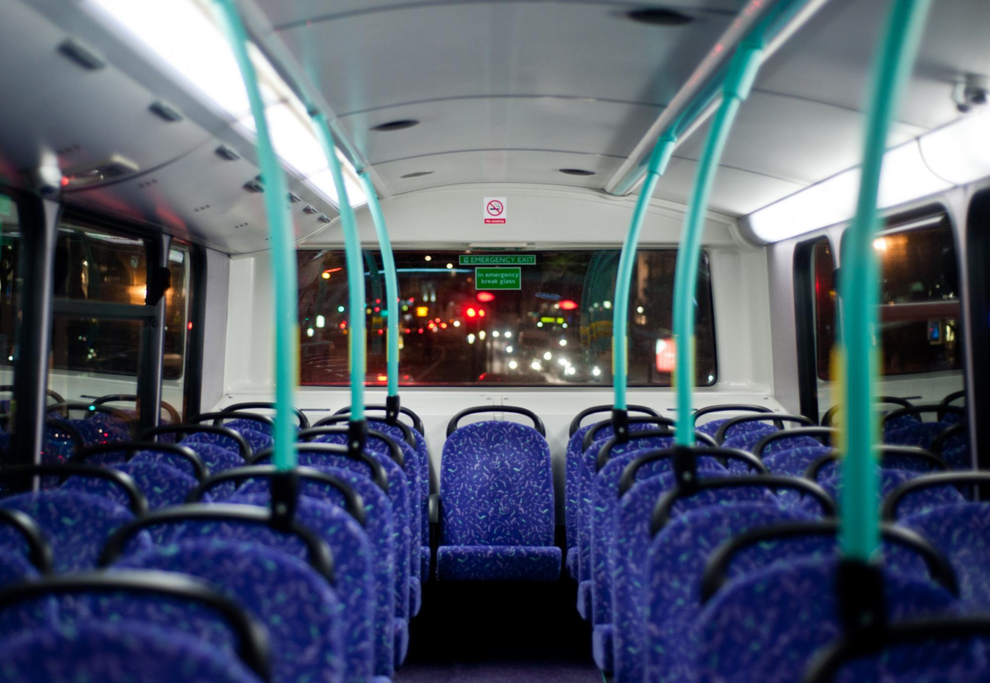 Rows of empty blue seats on a London Double Decker Bus at night