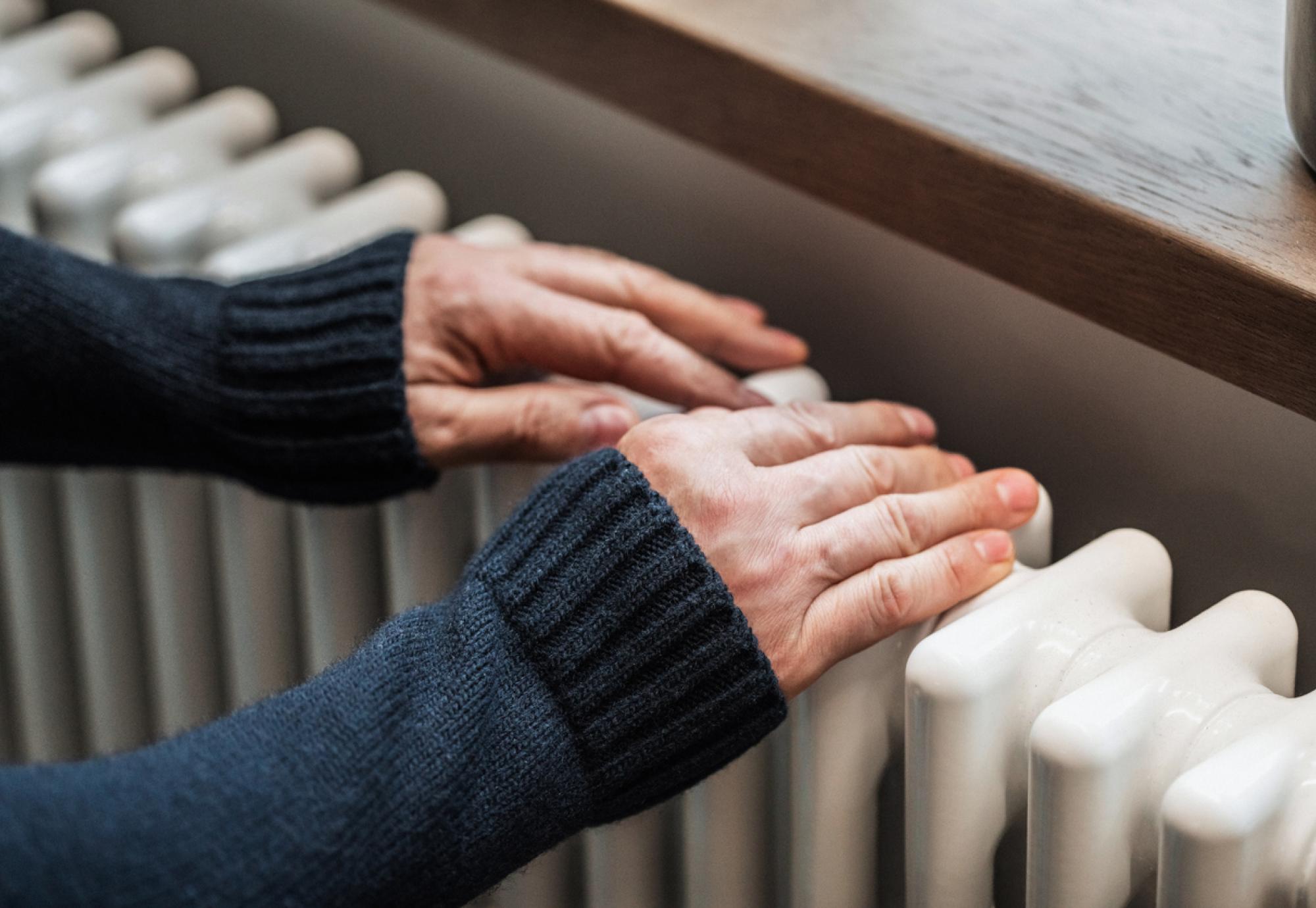 A man tries to warm his hands on a radiator