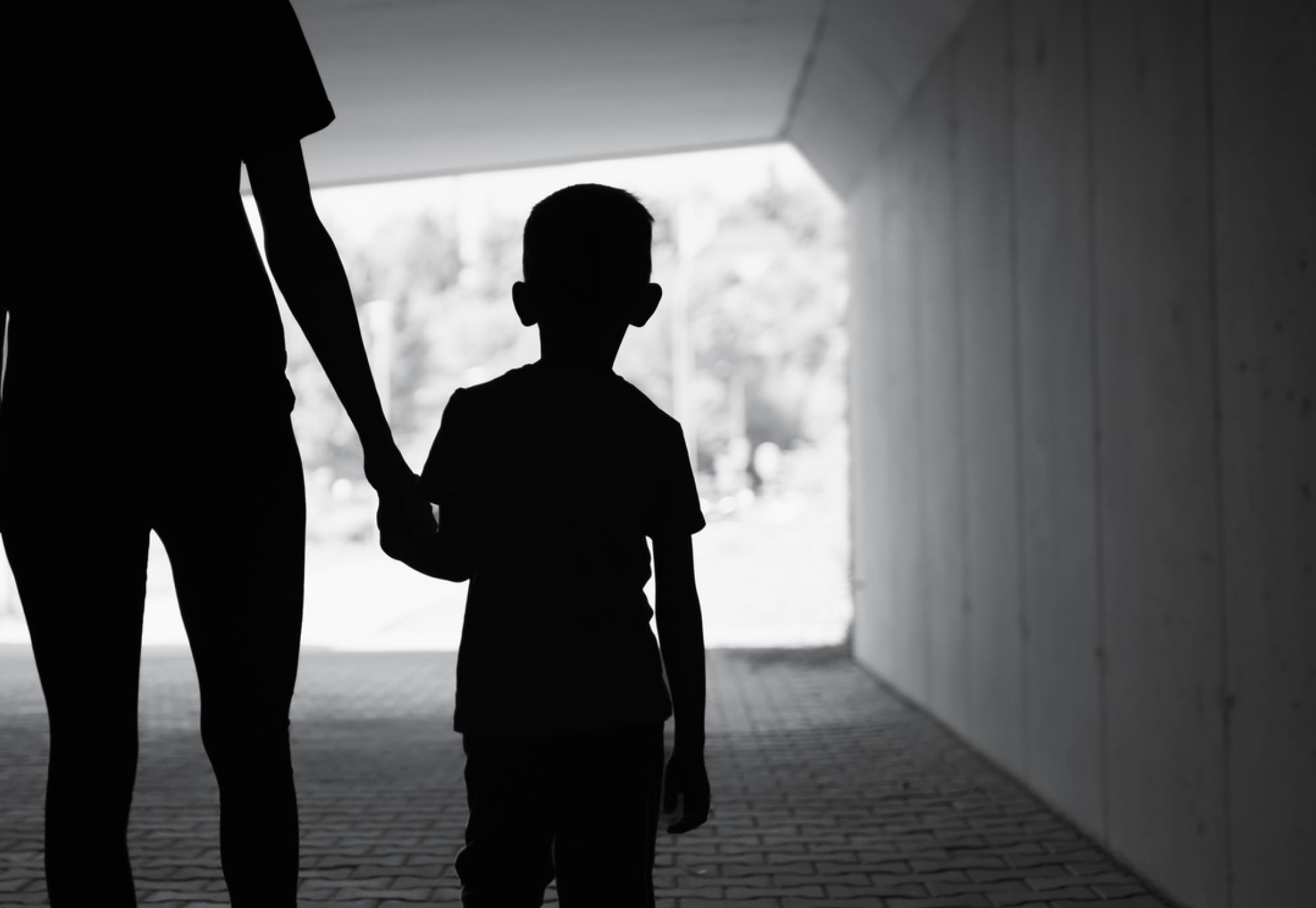 Poor child walking with single parent