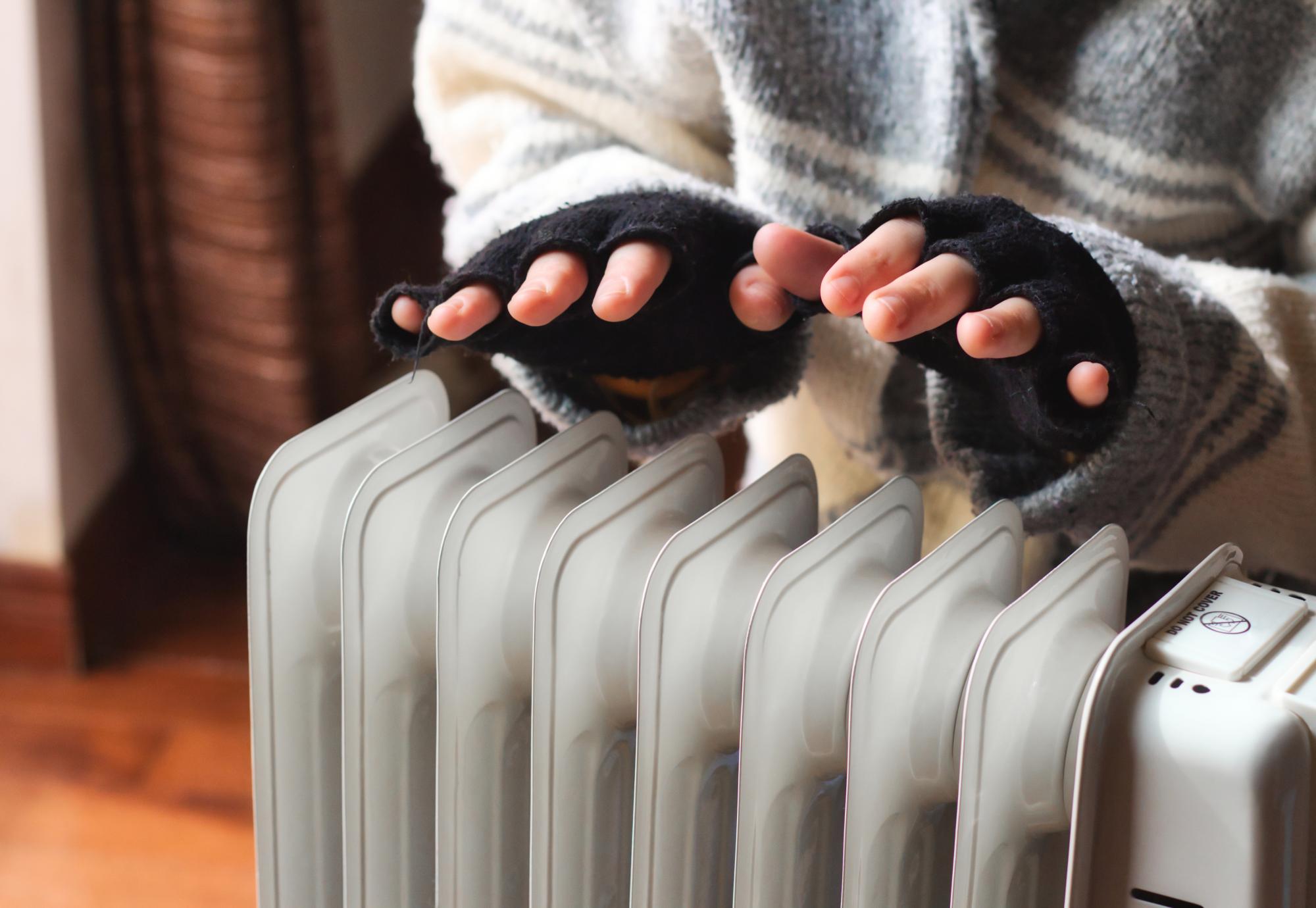 Woman heating her hands in her cold home