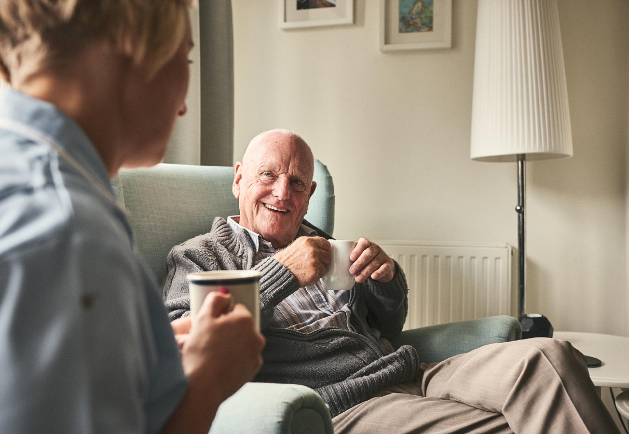 Smiling senior man talking to female caregiver