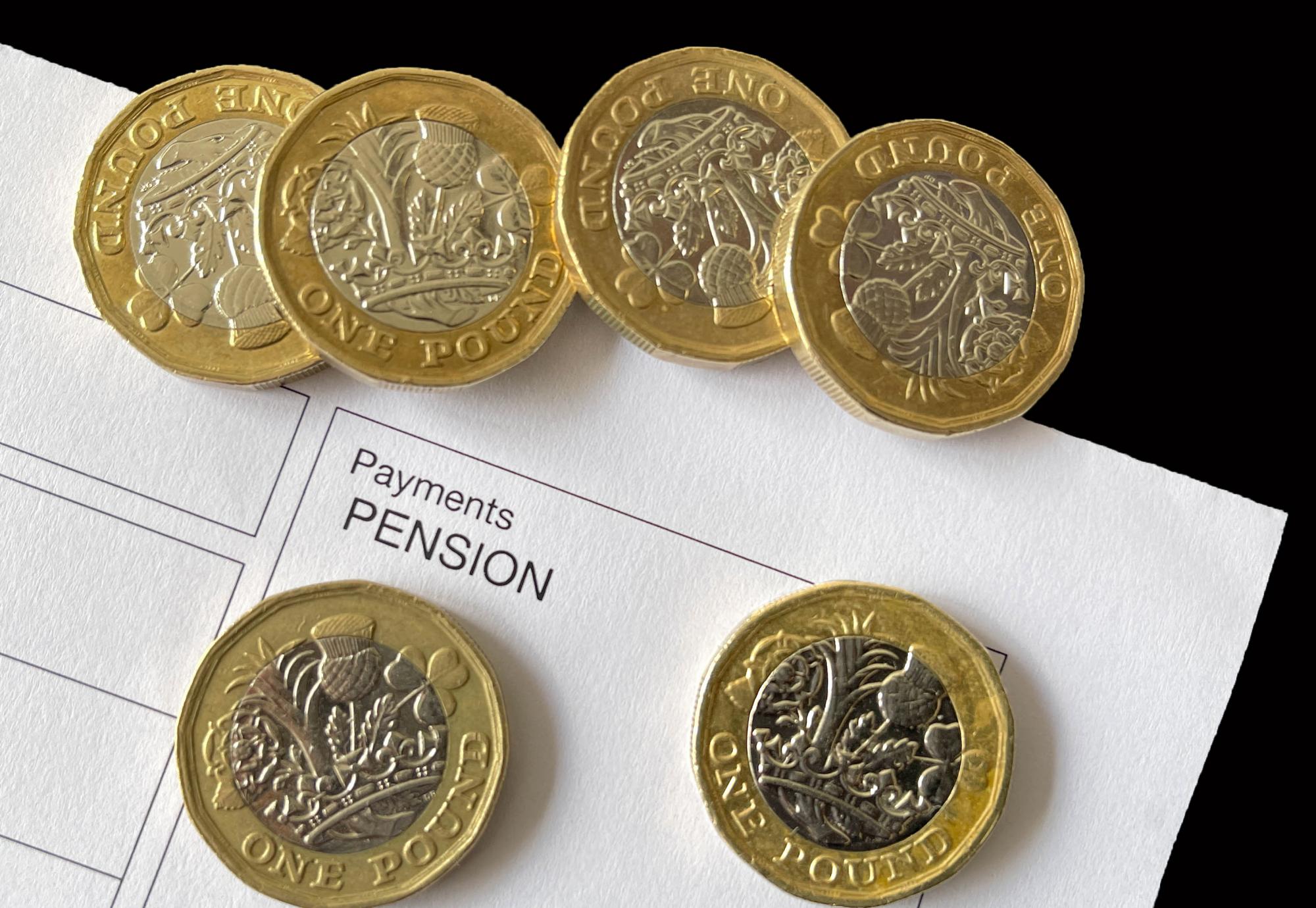 pound coins on top of an anonymous pension payment slip