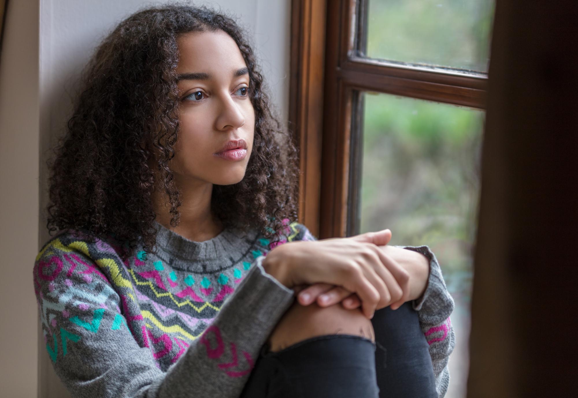 Vulnerable child sitting by window