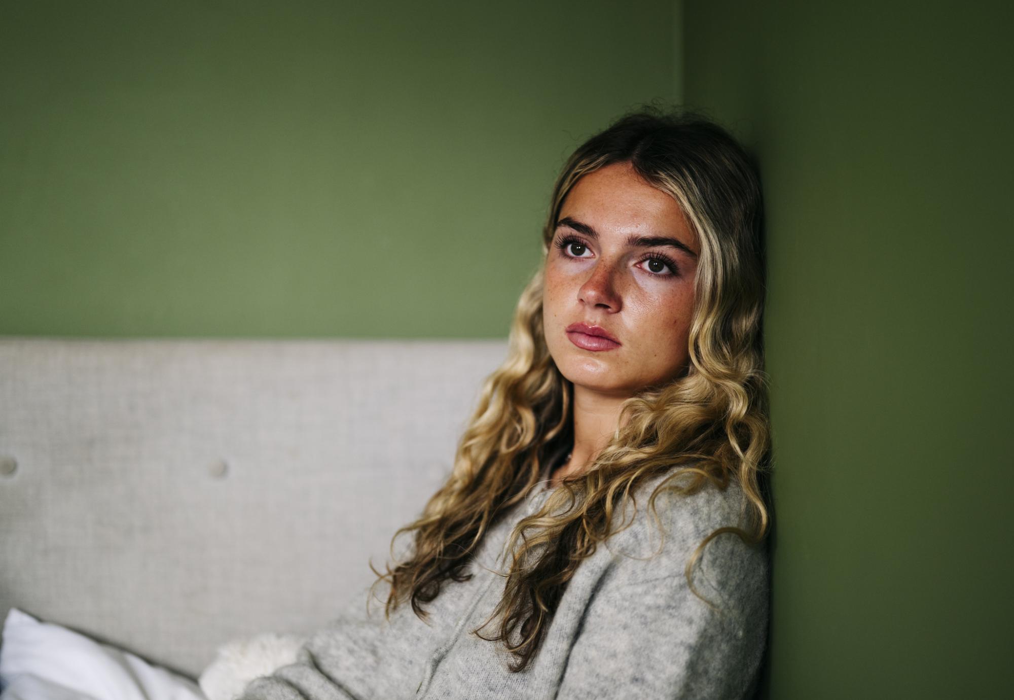 A teenage girl sat on the floor looking upset