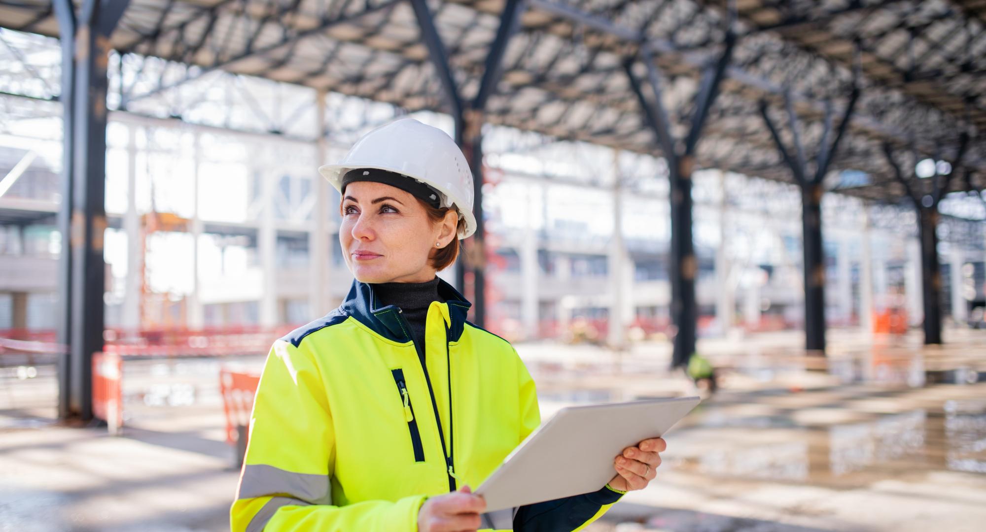 A woman engineer with tablet standing on construction site, working.