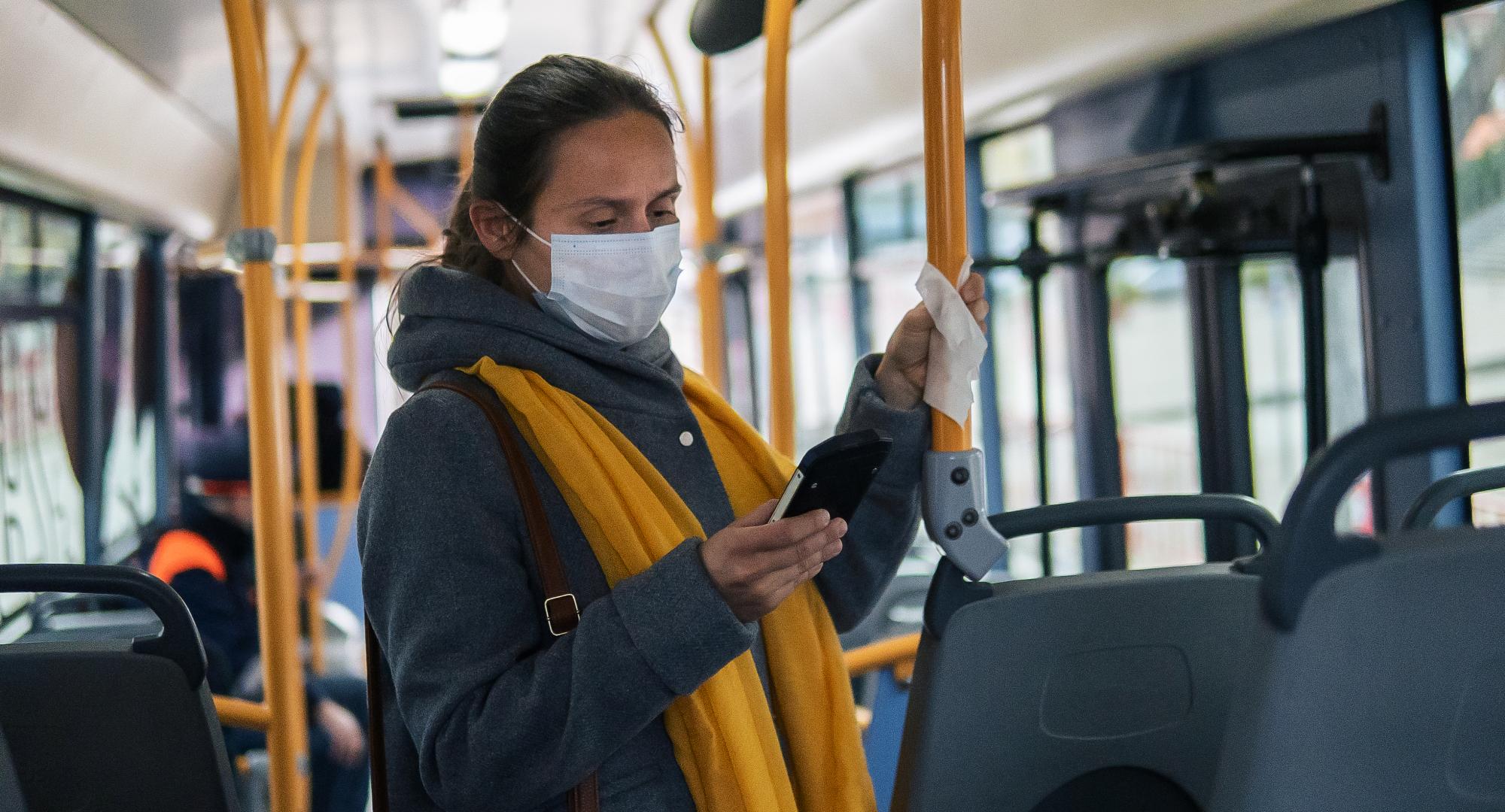 Woman stands  on bus in mask
