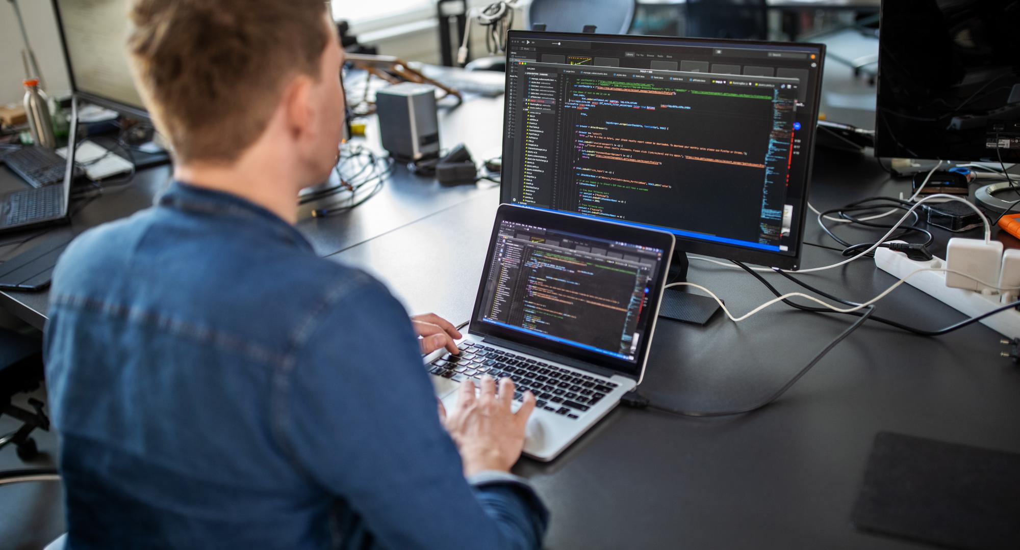 Man sits at computer coding.