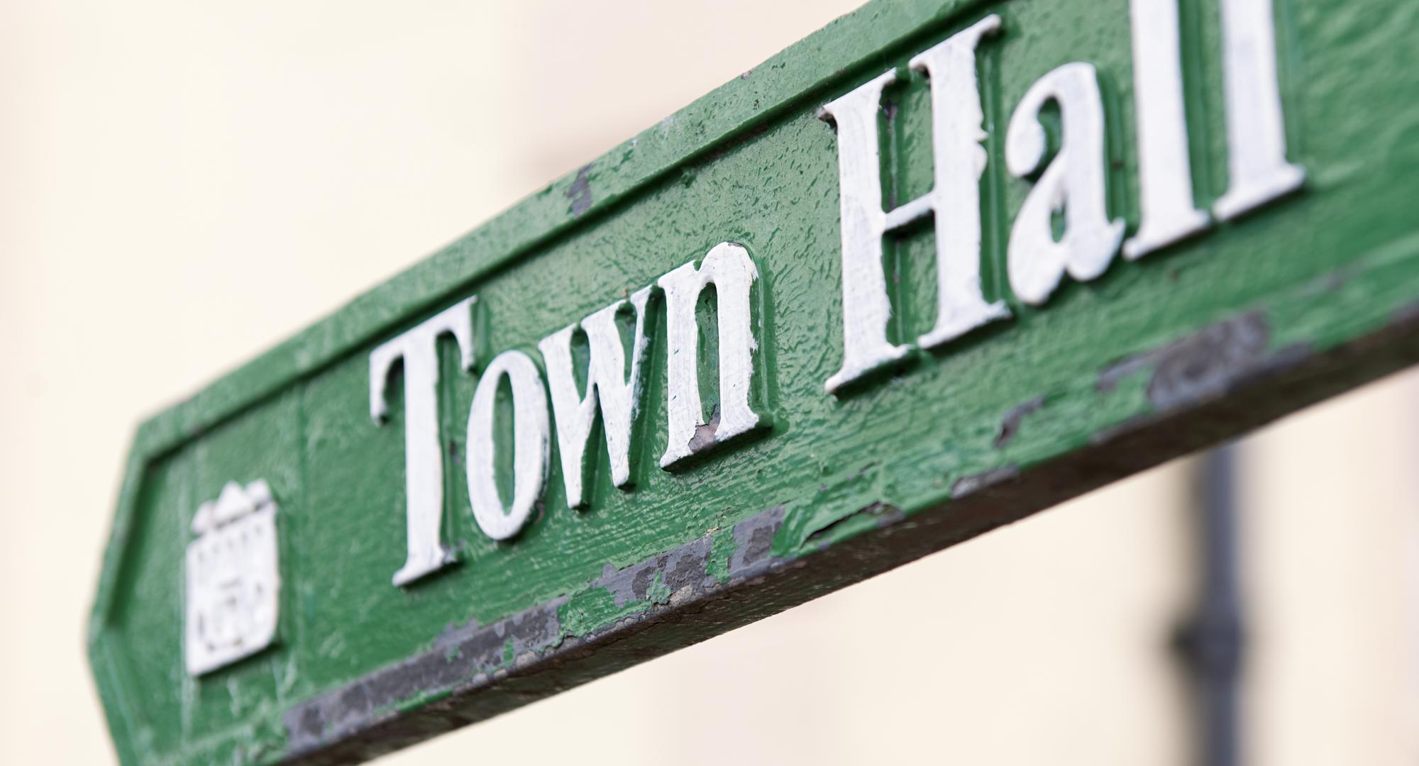 Close-up of a traditional, worn sign showing the direction to the town hall.