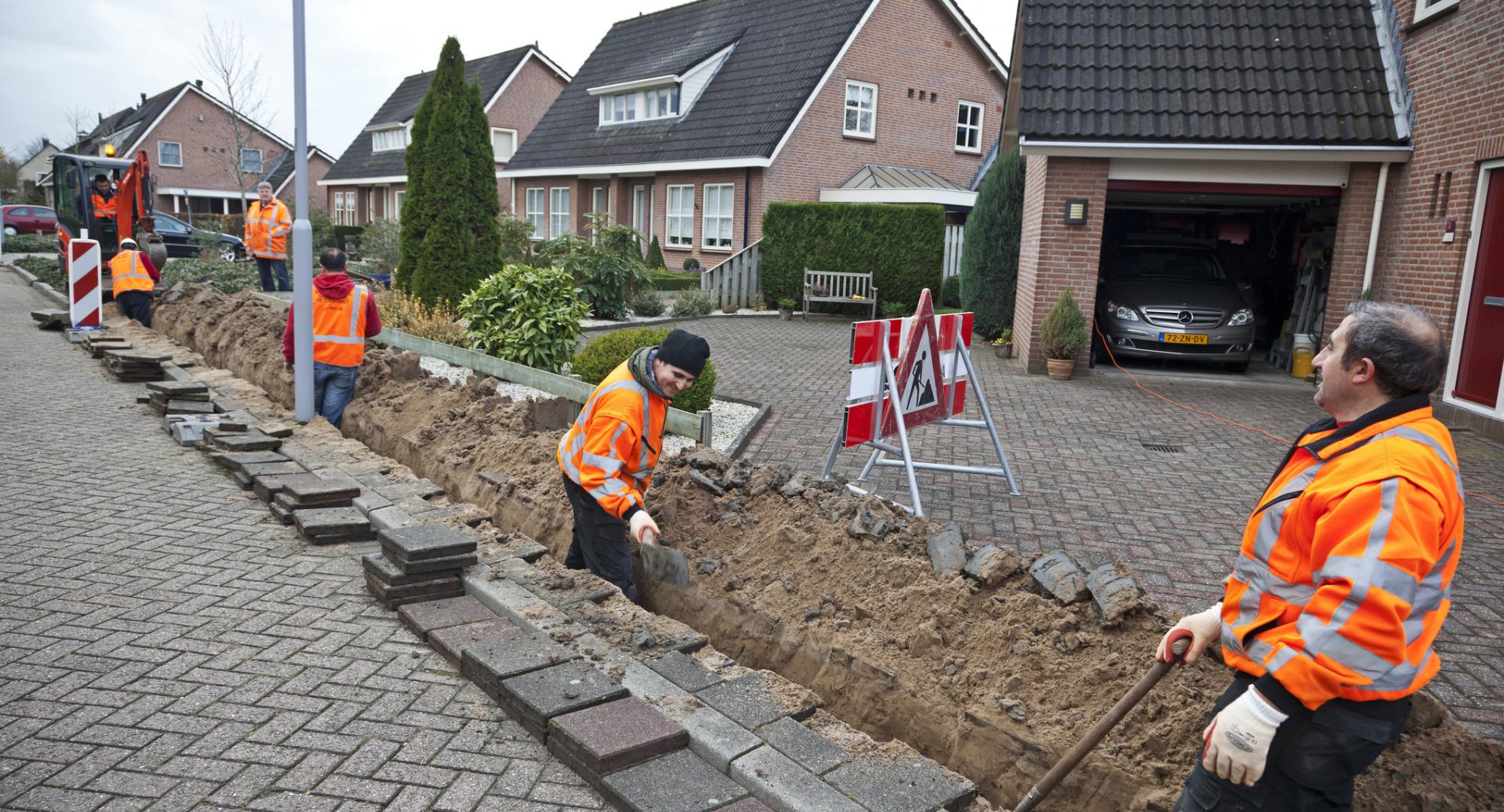 Workmen bring up pavement to lay fibre optic cables.