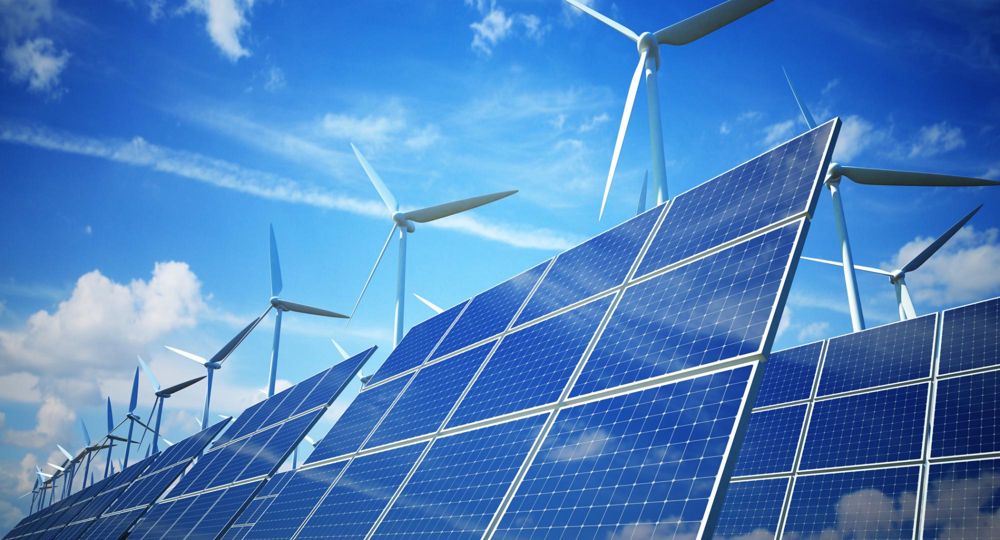 Solar plant in the sun with wind turbines in the backgroud.