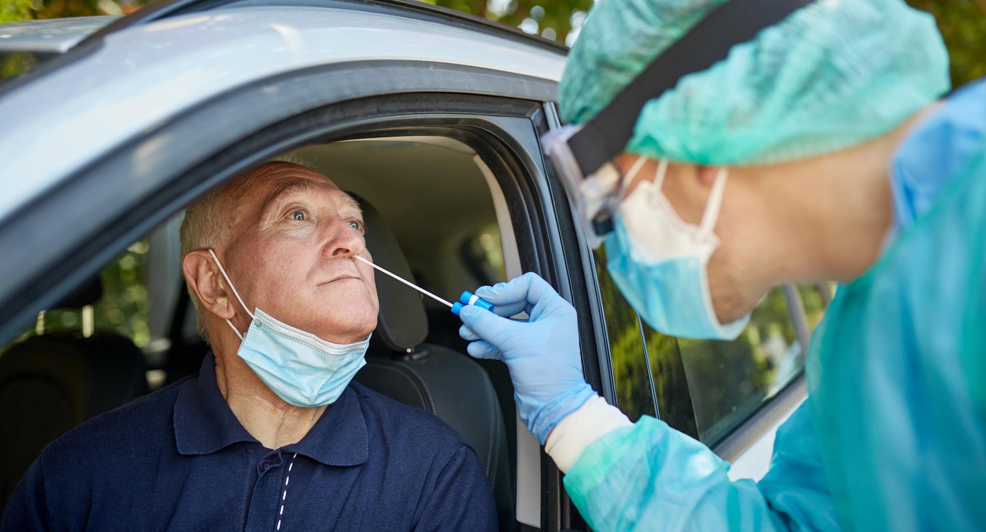 Man receives Covid-19 test from woman wearing full PPE