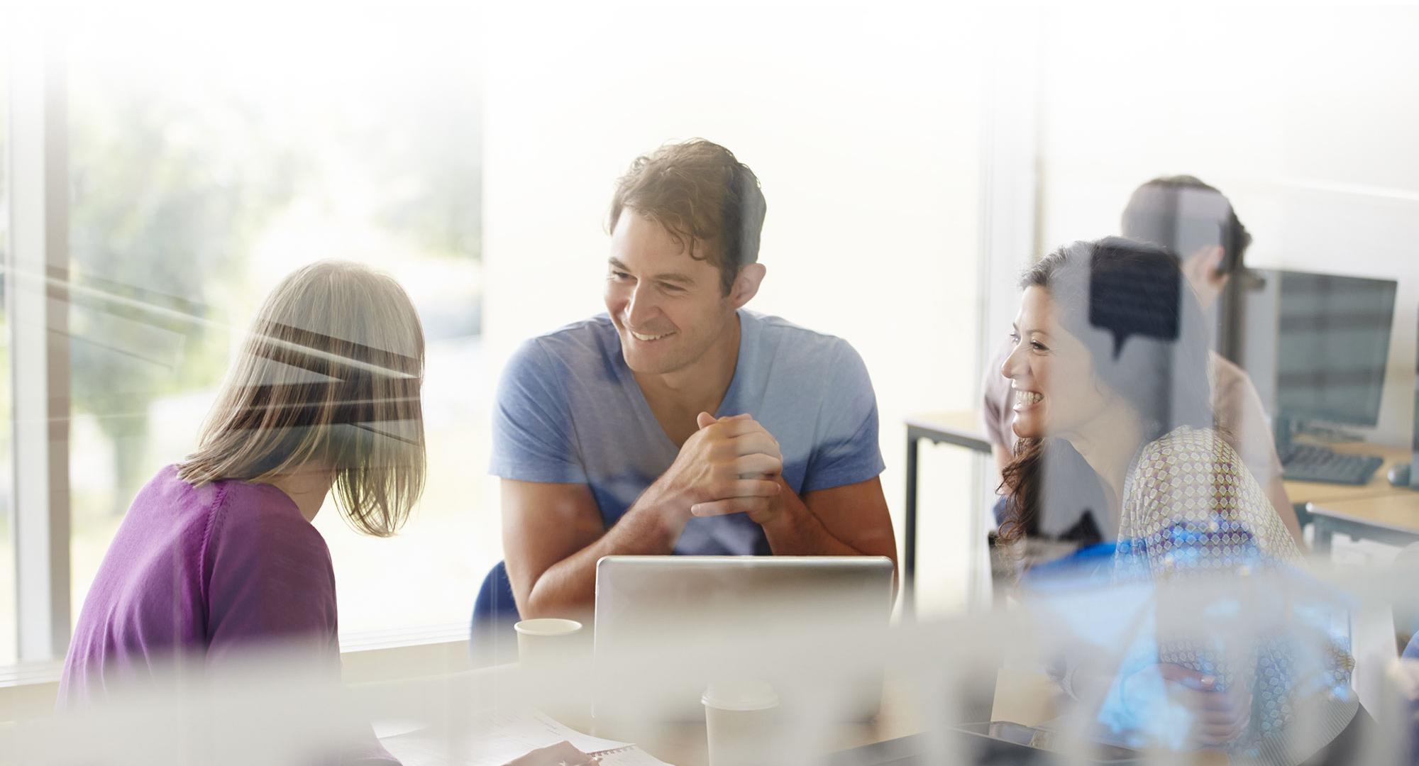 Colleagues sit and chat over office work.