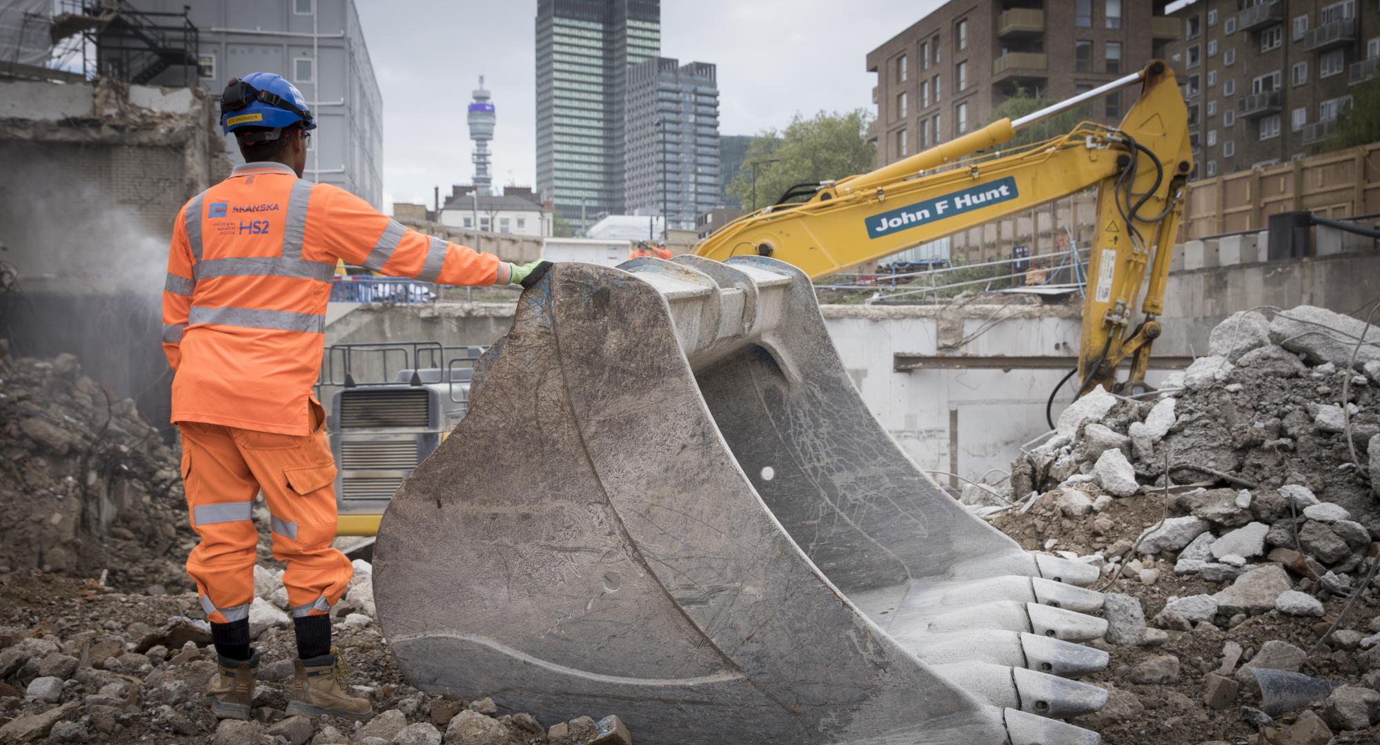 Man stands next to digger working on HS2 at London Euston