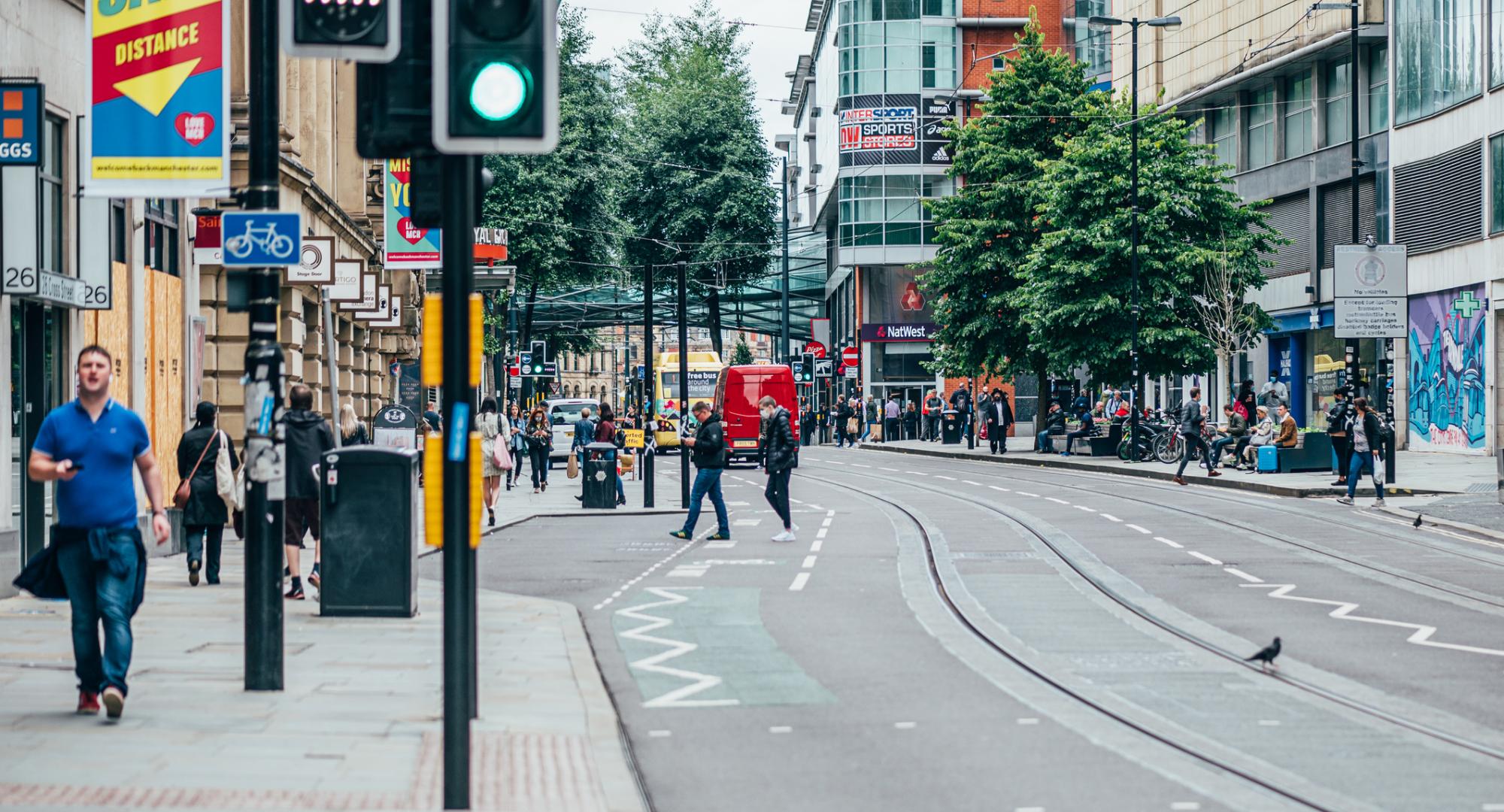 Busy Manchester street with pedestrians on the pavement.