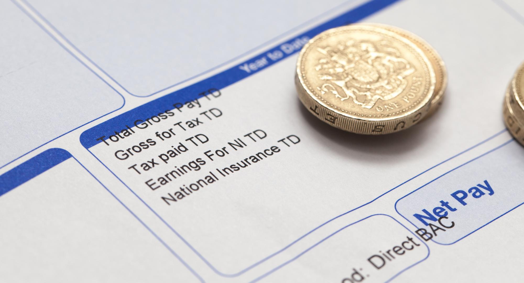 Pay cheque with pound coins on.