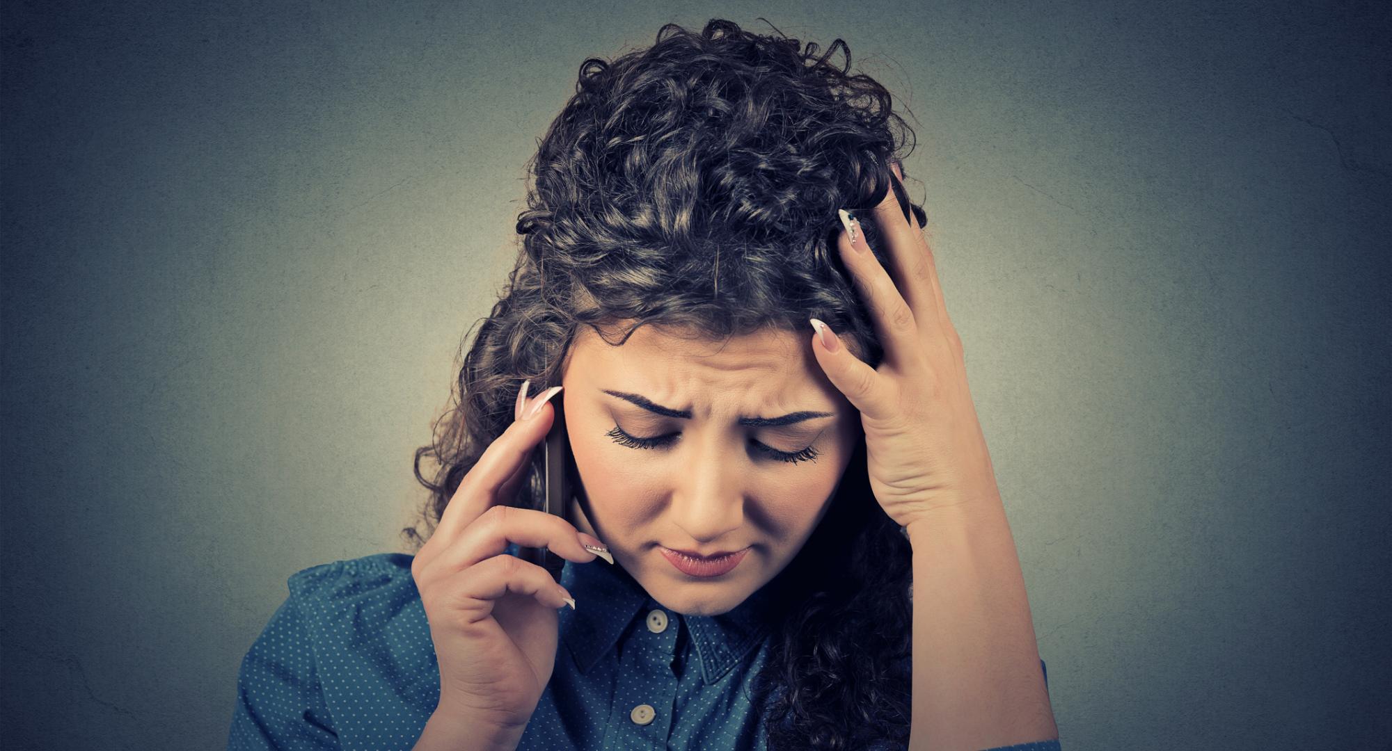 Woman looks distressed on the phone to helpline.