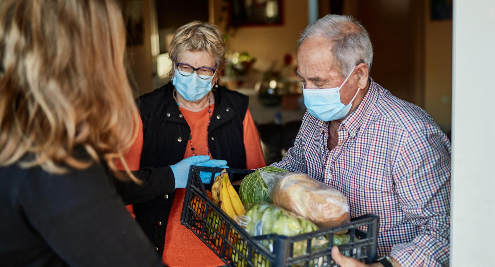 Elderly couple get their food delivery by social care worker.