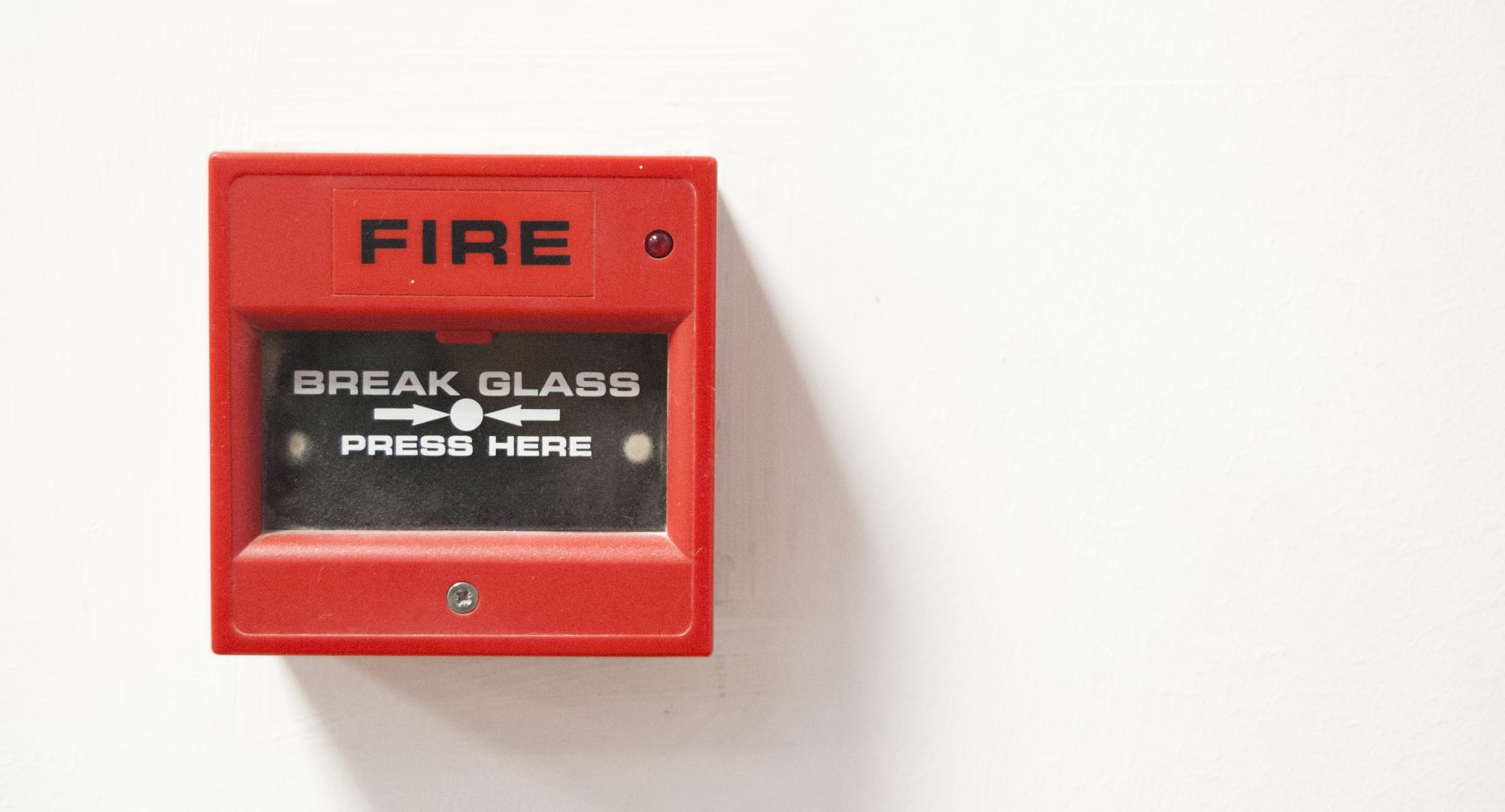 Fire alarm sits on wall ready to be activated. 