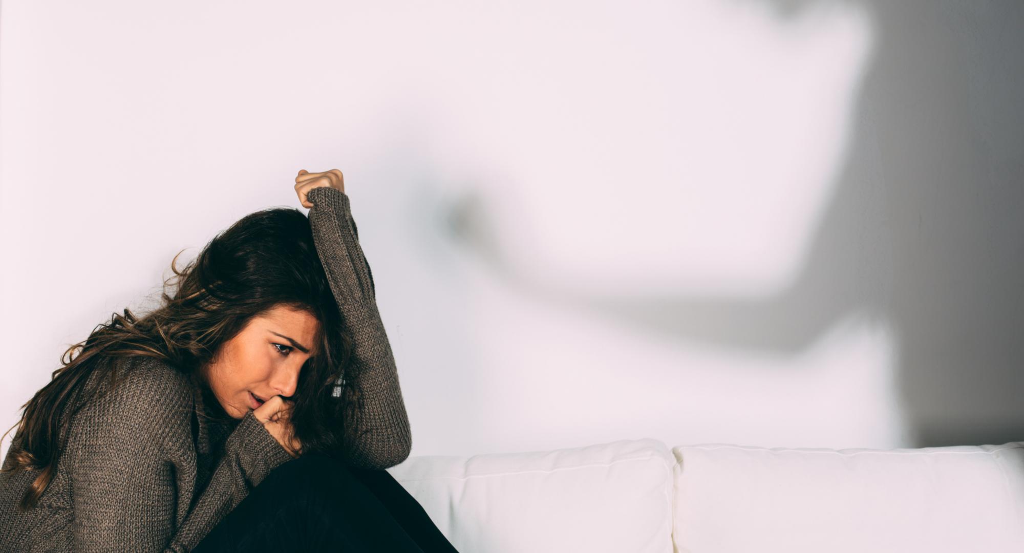 Woman cowers from her abuser. 