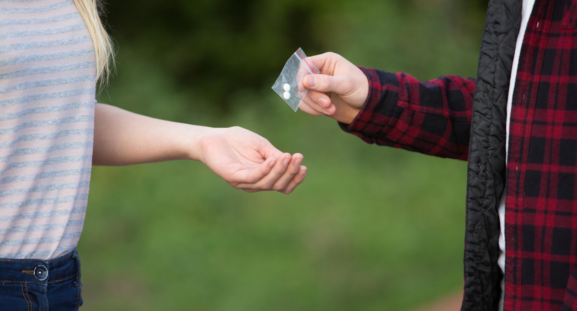 Man hands pills to woman.