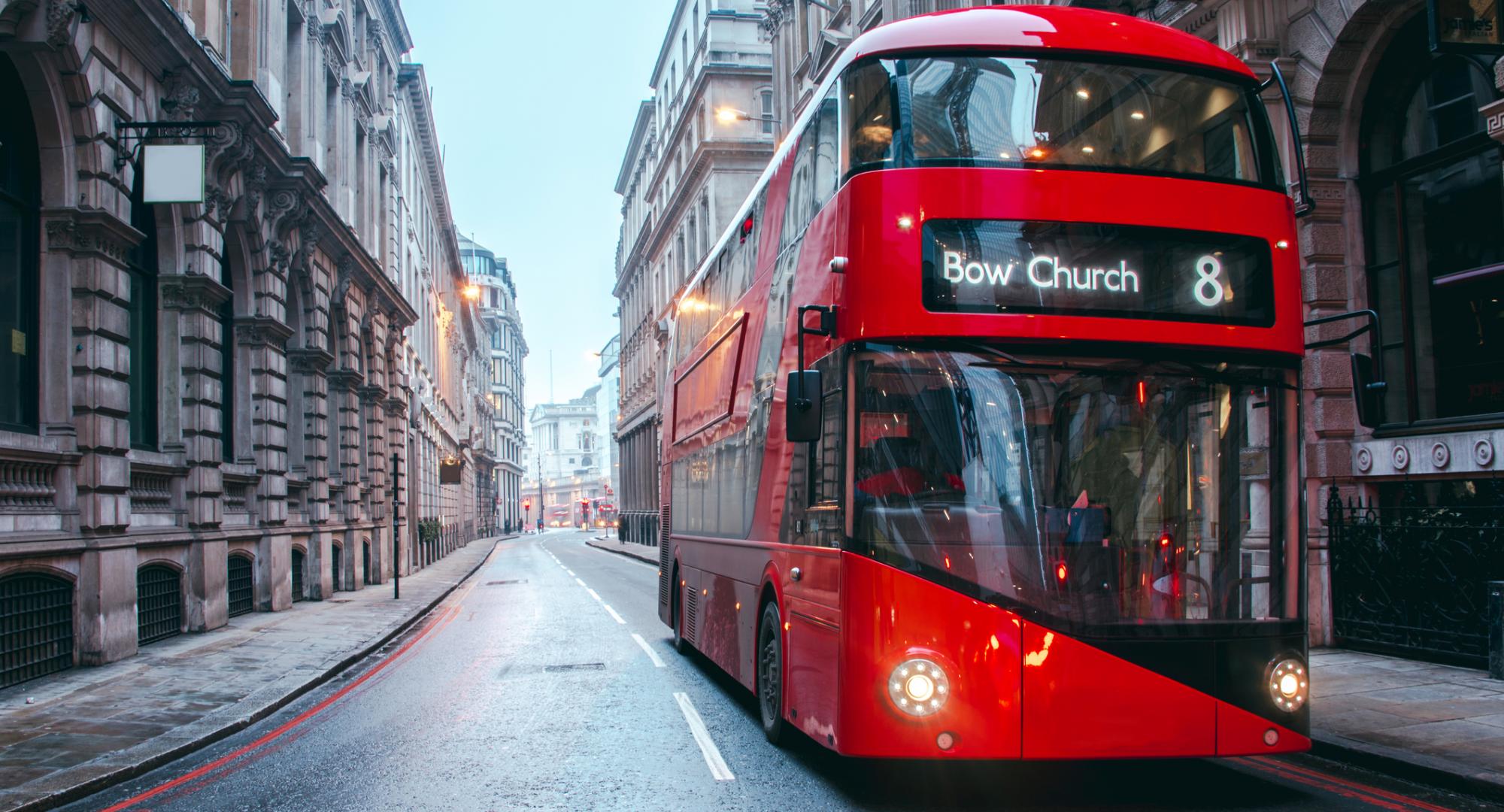 Bus drives down empty London street. 