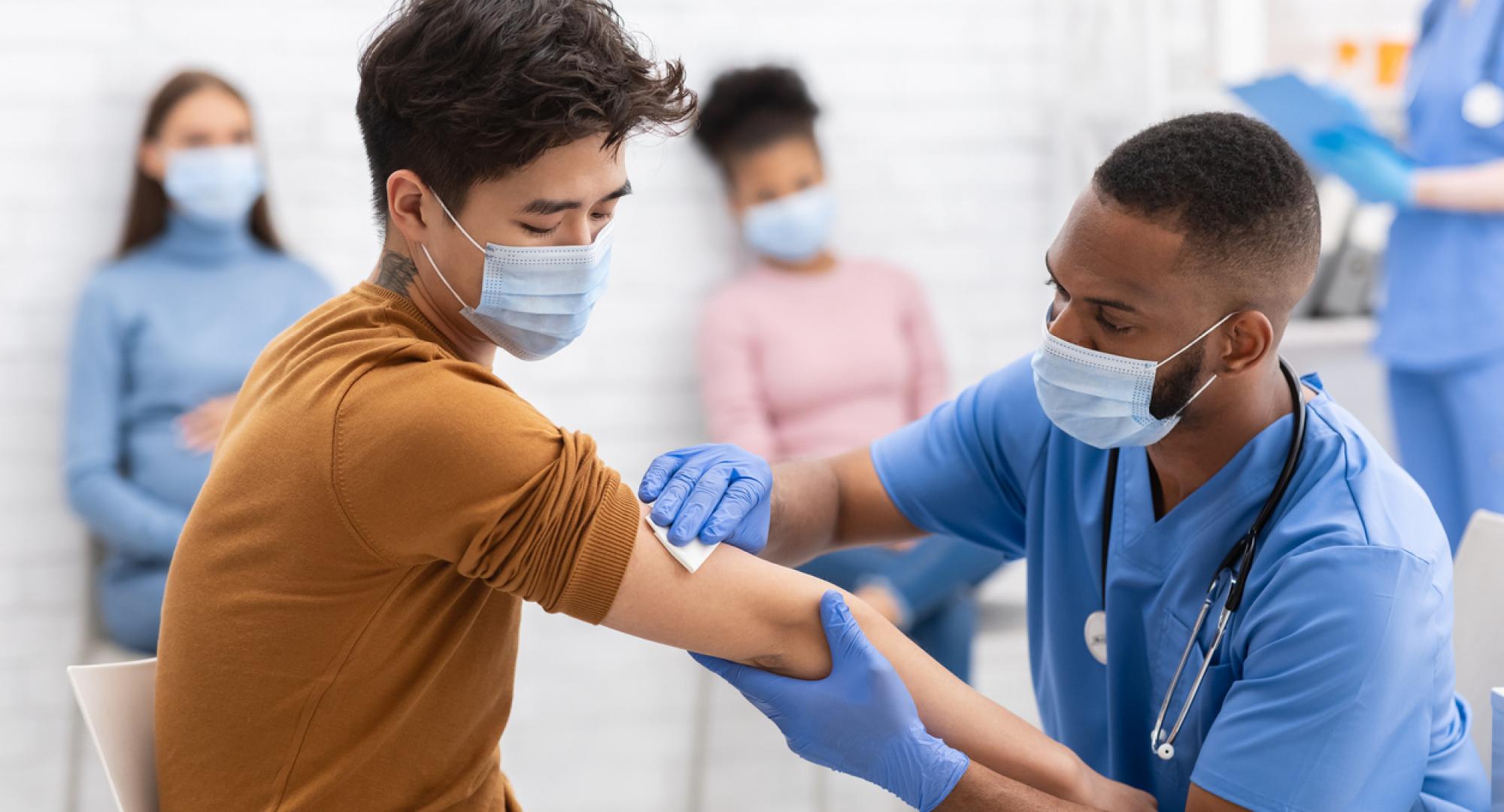BAME man receives vaccine from nurse.