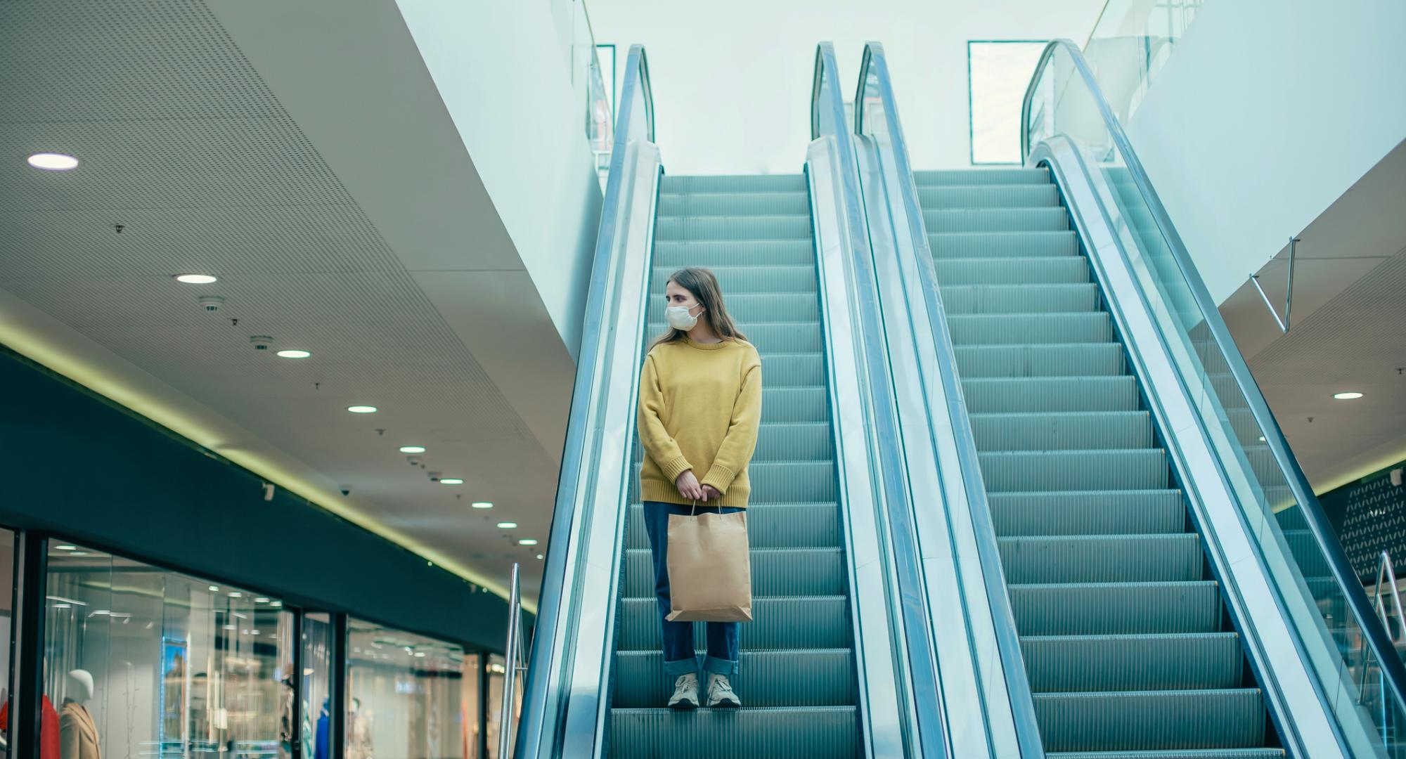 Woman standing on shopping centre escalators