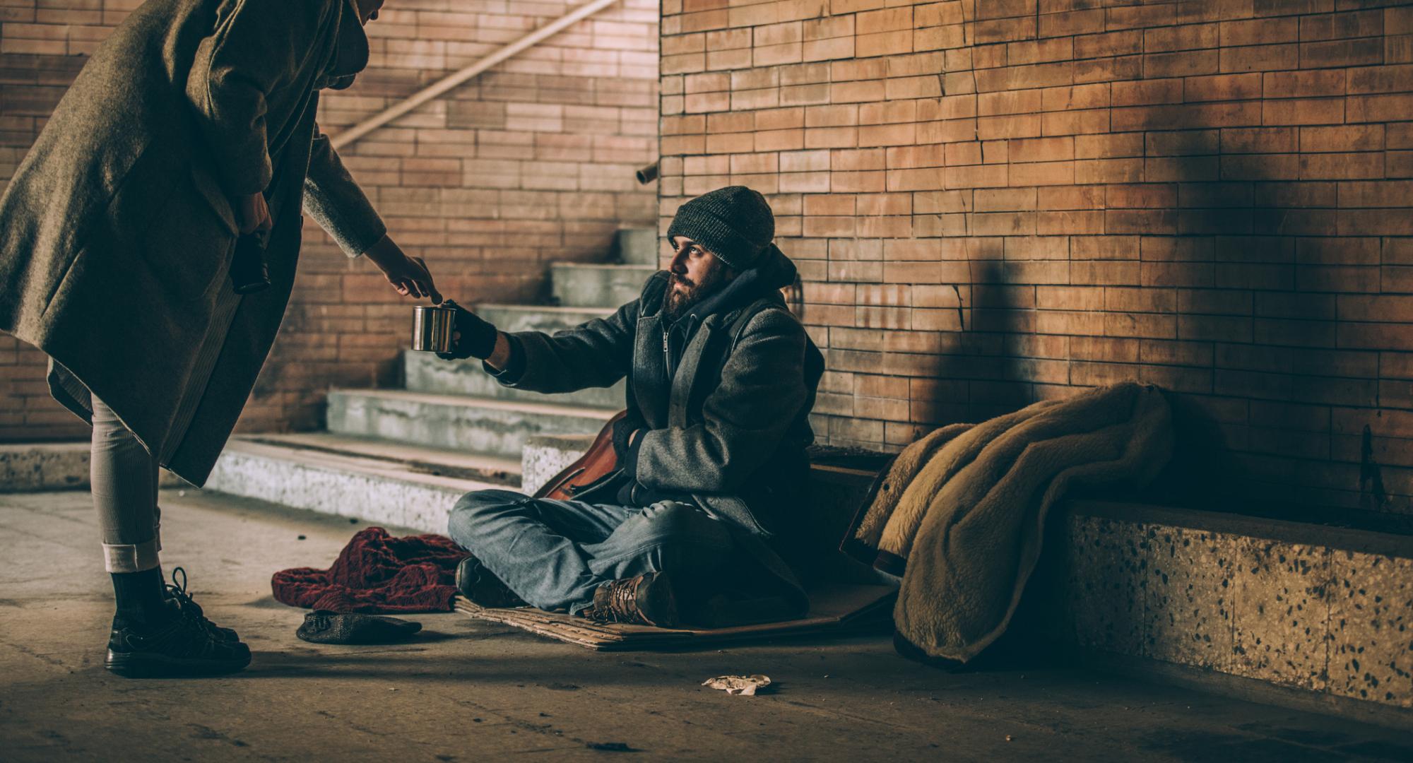 Homeless man and woman giving him money